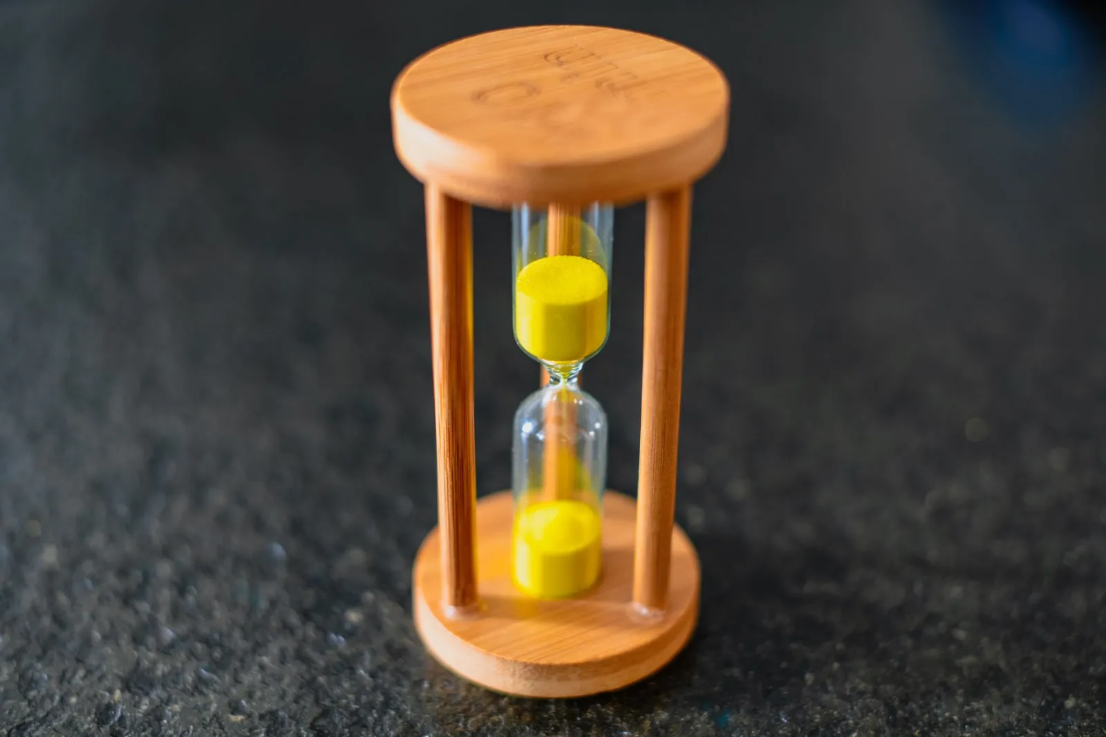 A small wooden hourglass with yellow sand