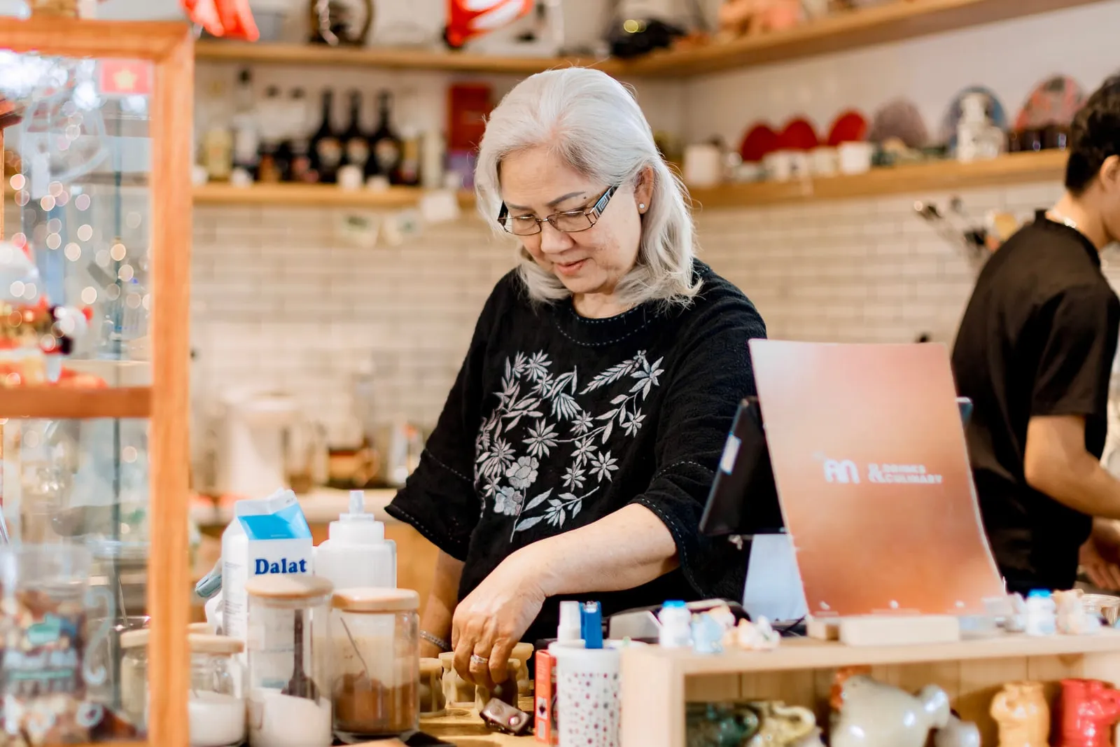A shop owner working behind a counter beside a point-of-sale tablet