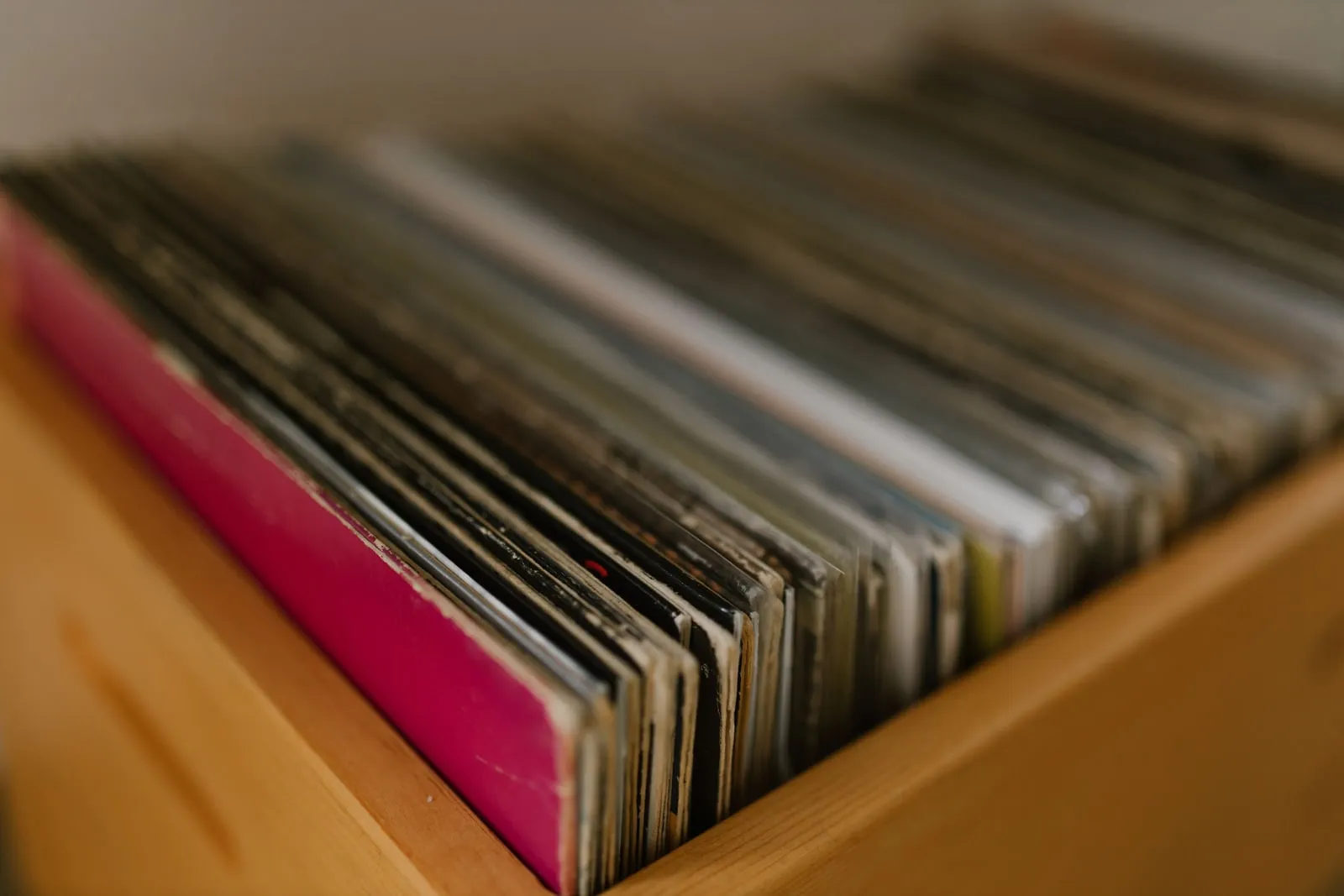 Vinyl record sleeves standing in a row in a wooden crate