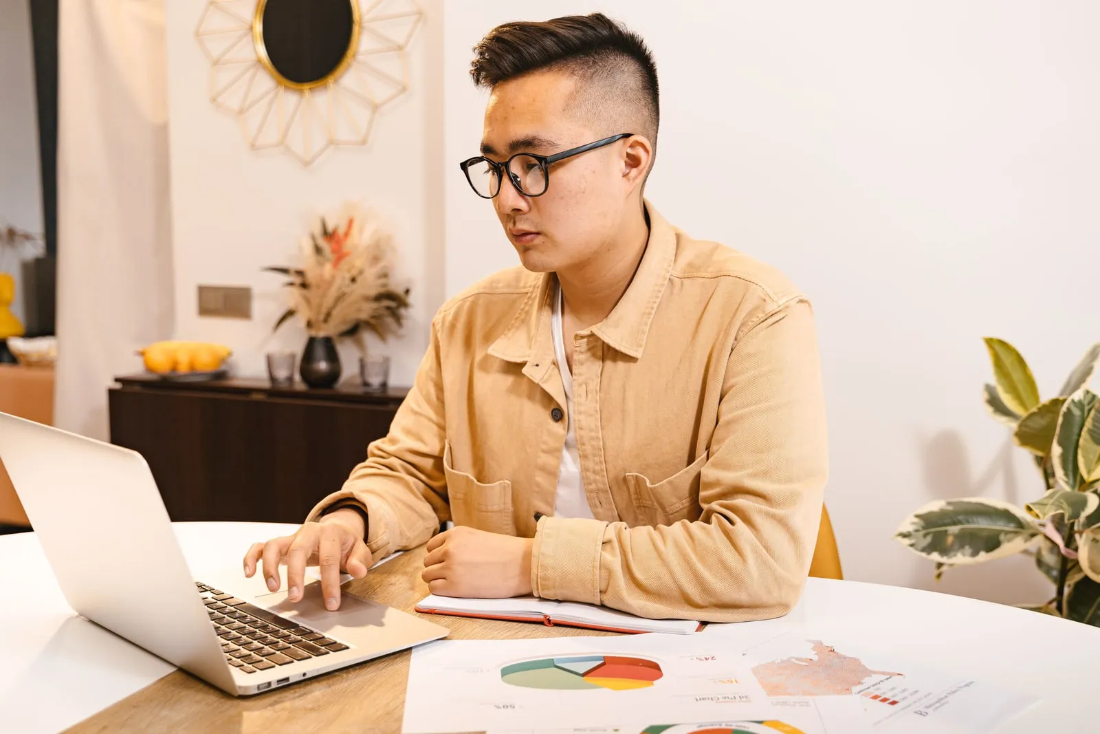 A person working on a laptop with documents at a desk