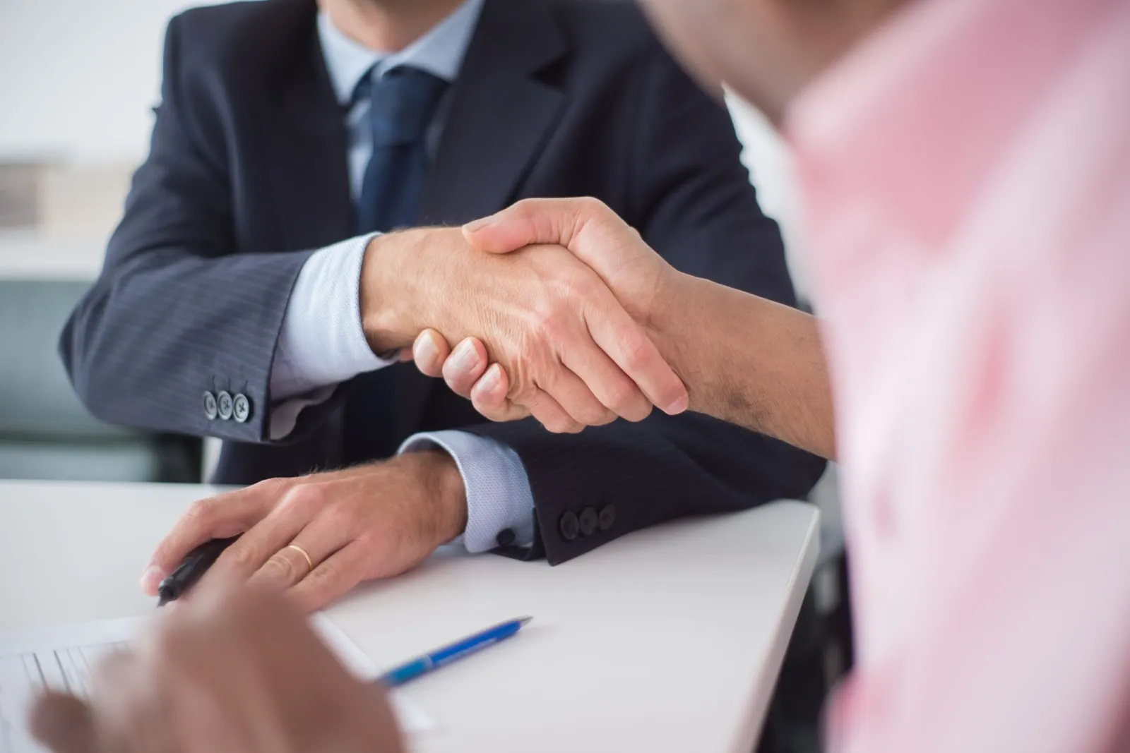 Two people shaking hands across a table