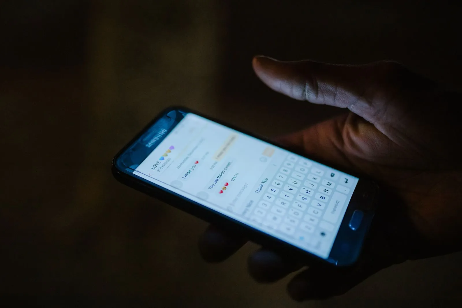 Hands typing a message on a phone keyboard
