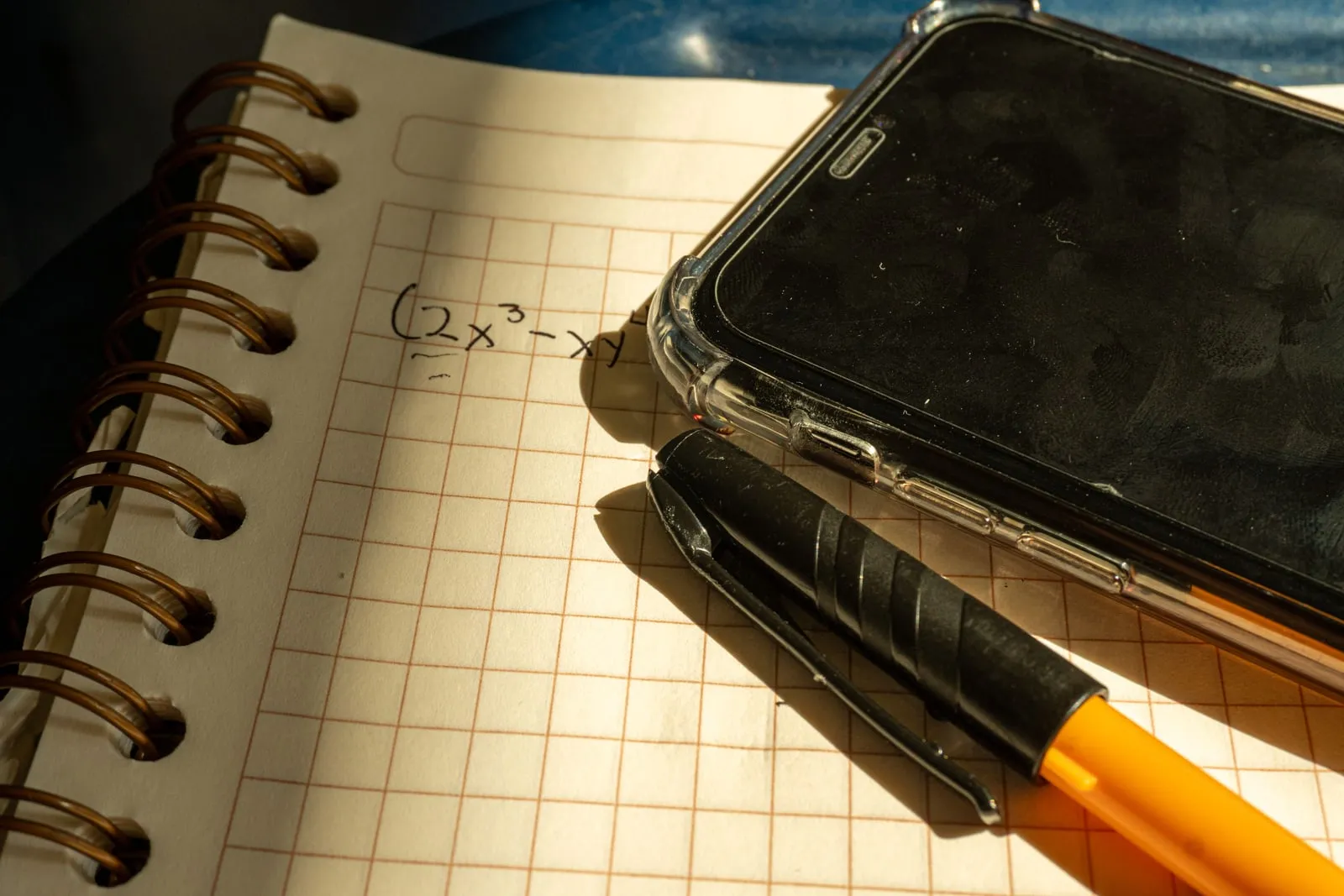 A notebook of handwritten mathematical notes beside a pen