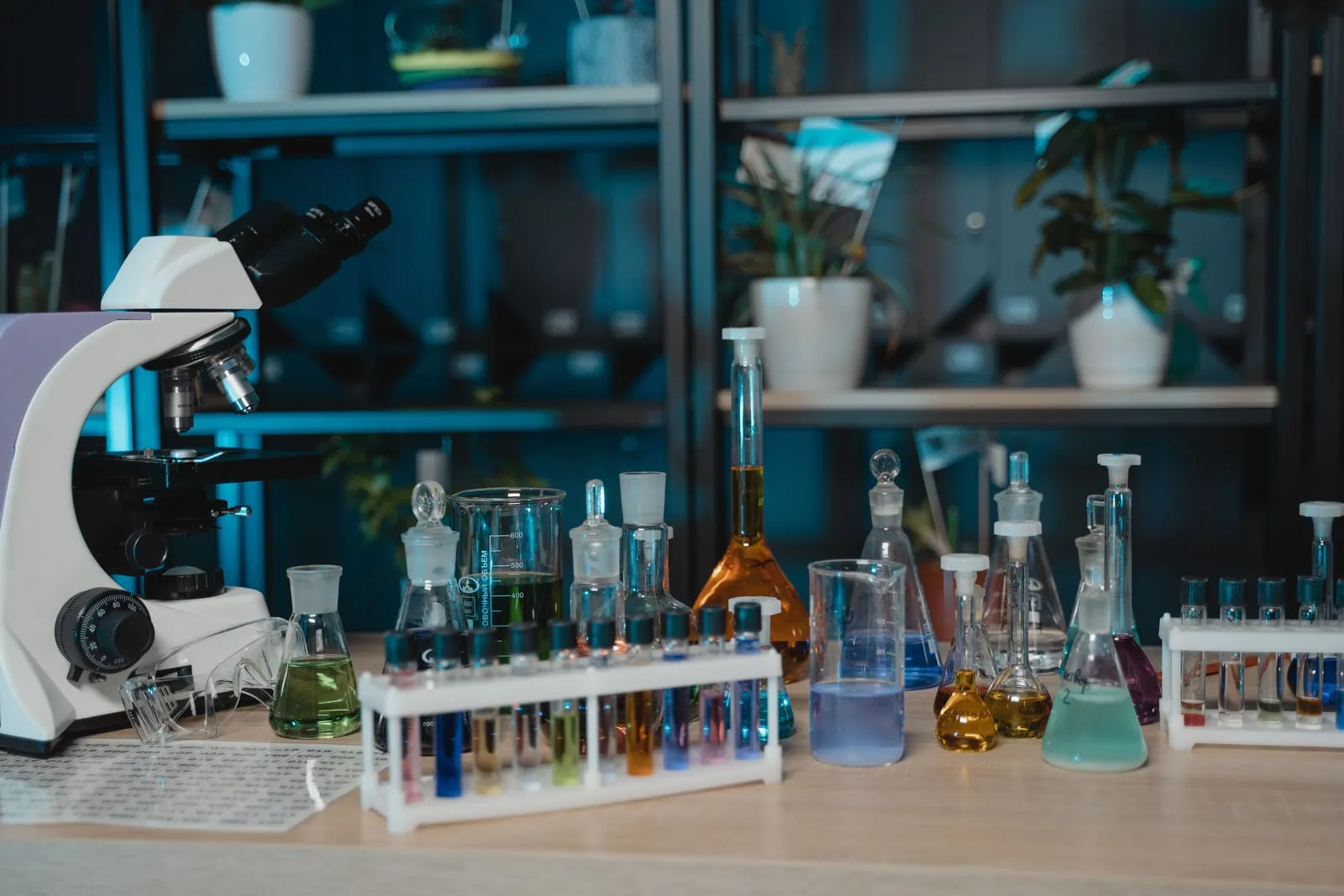 Um microscópio ao lado de suportes de tubos de ensaio e balões numa bancada de laboratório
