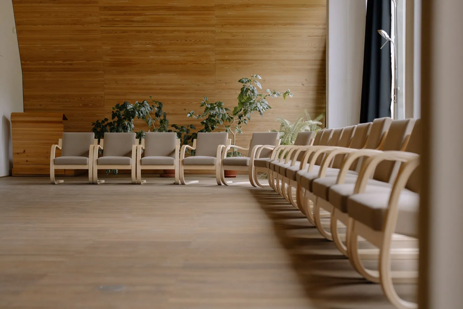 Empty wooden chairs arranged in rows in a panelled hall