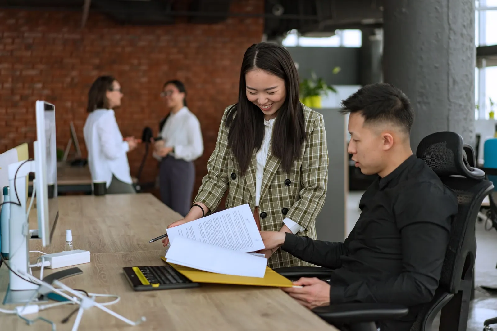 Two colleagues going through printed documents together at an office desk