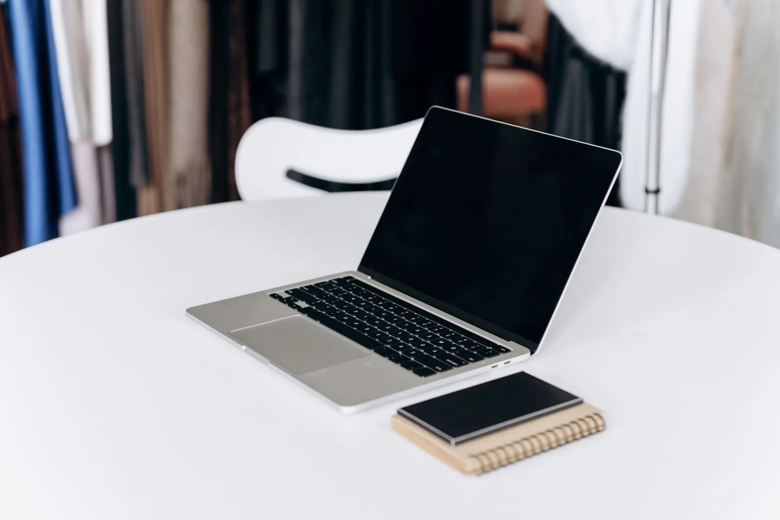 An open laptop and a notebook on a white table