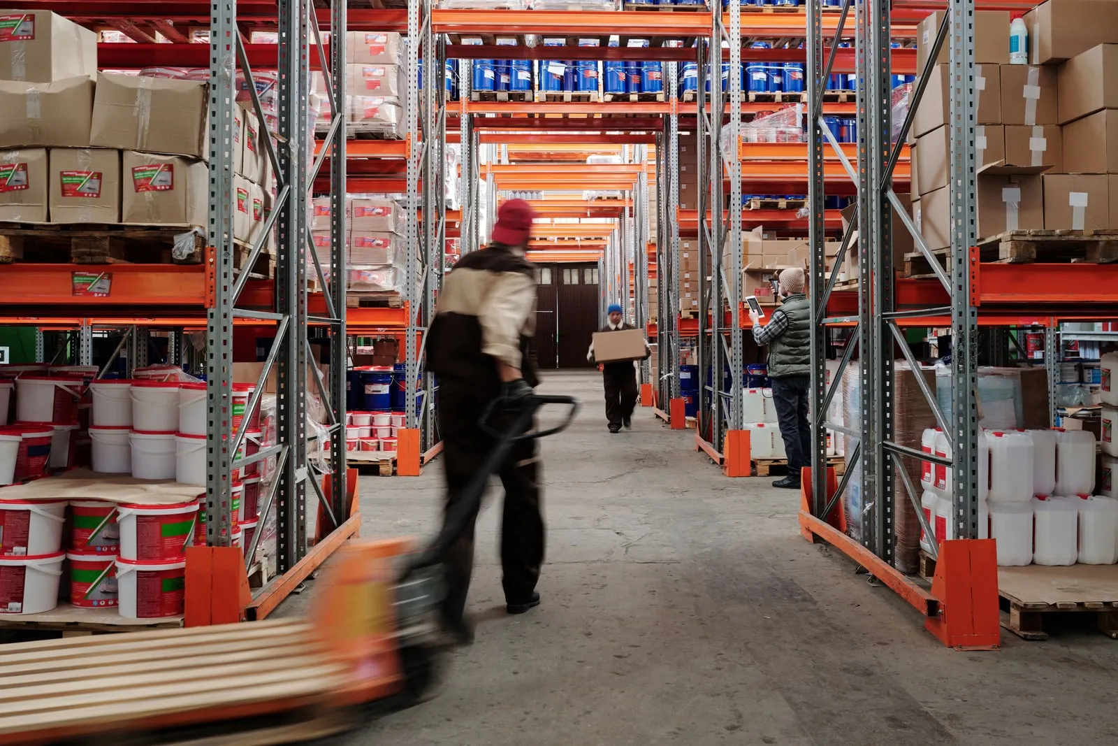 Warehouse workers moving boxes among tall shelving