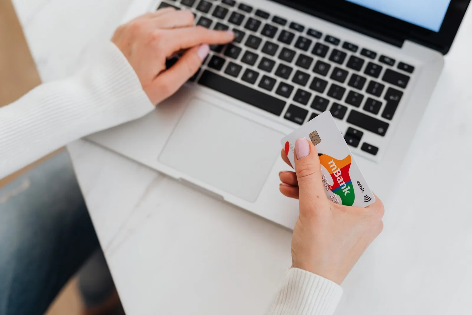Hands holding a credit card in front of a laptop