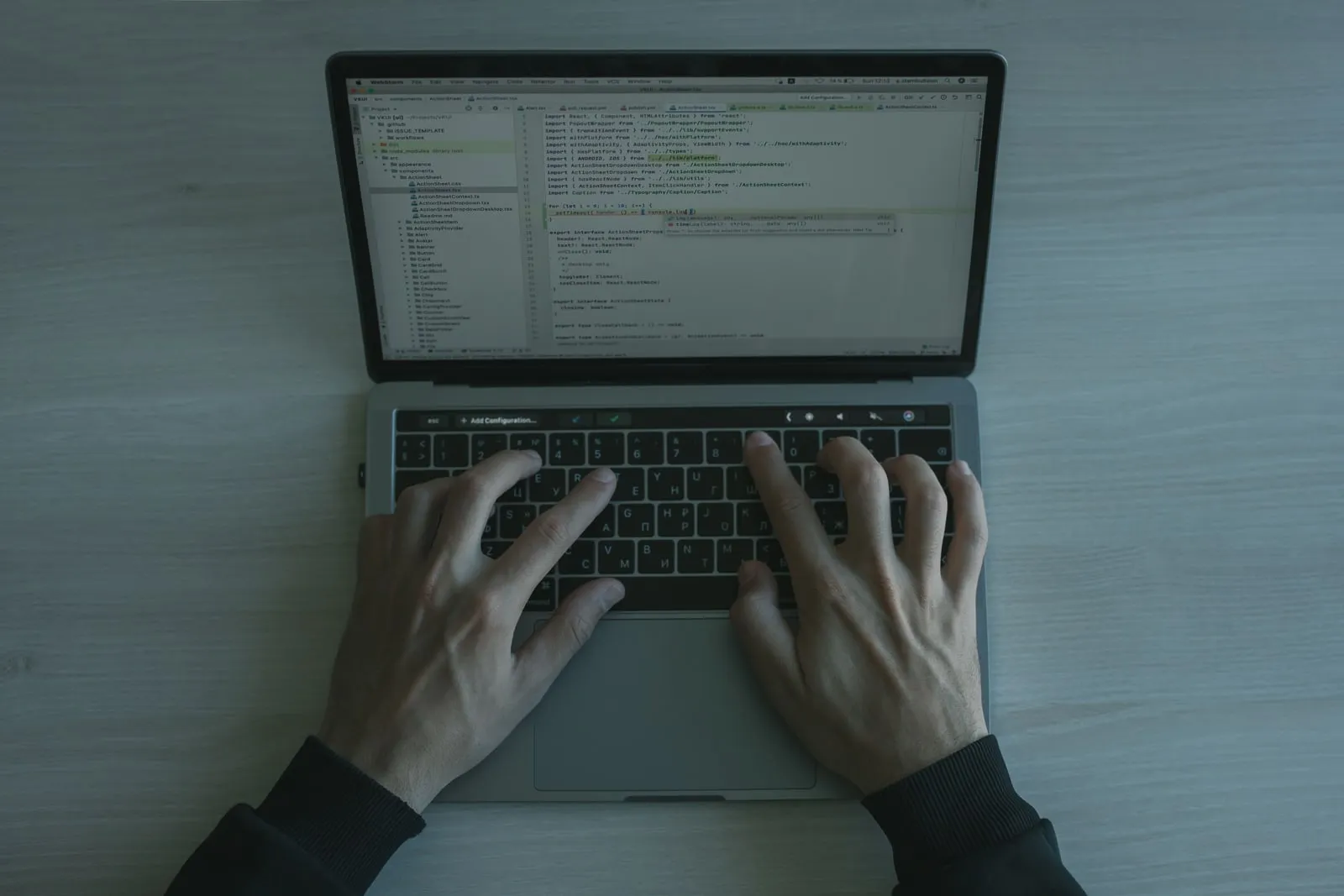 A developer typing at a keyboard with code on the monitor