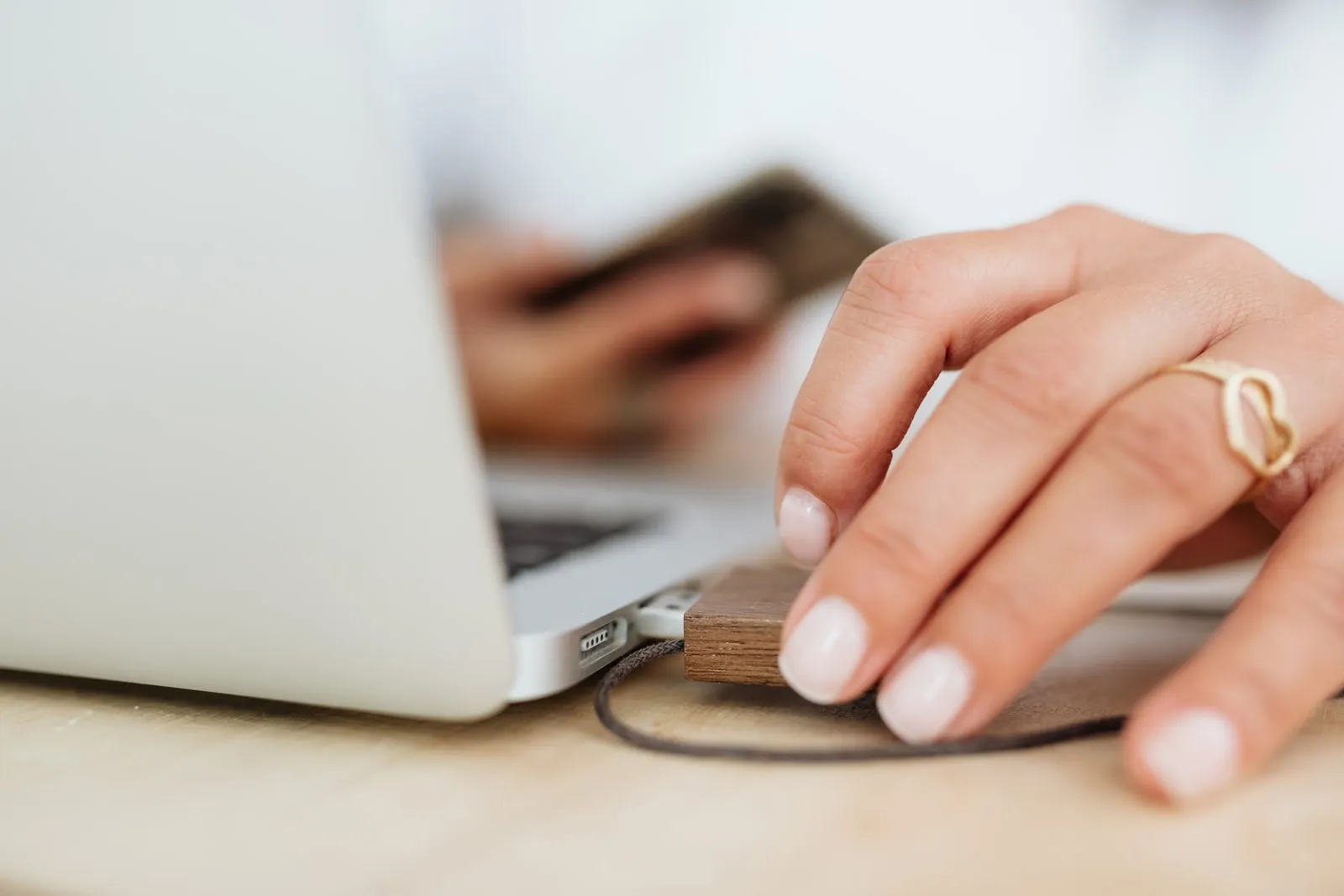 A hand plugging a small wooden USB drive into a laptop
