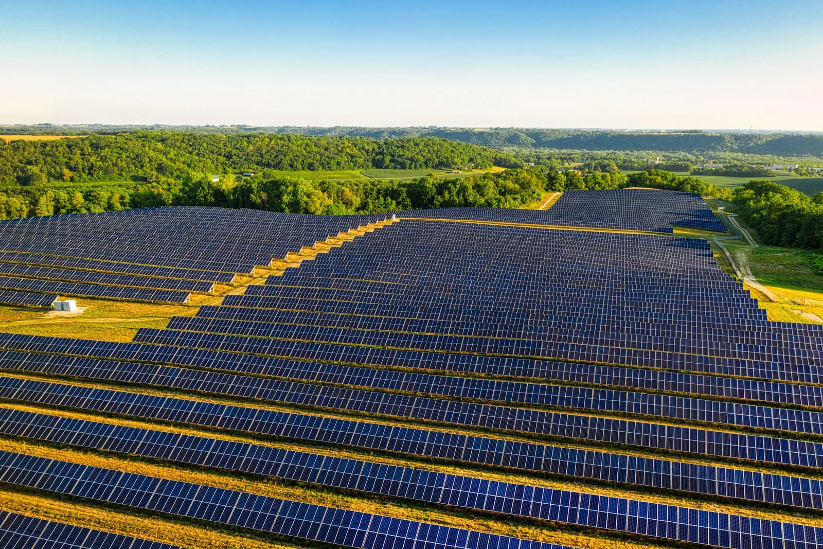 An aerial view of rows of solar panels across open farmland