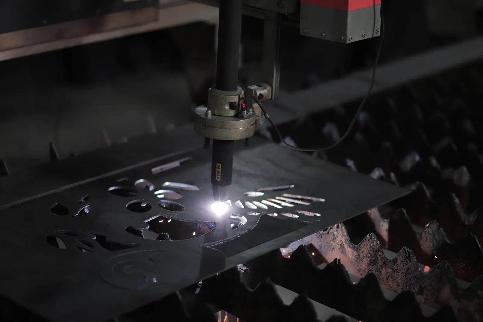 A computer-controlled cutting head working on a steel sheet