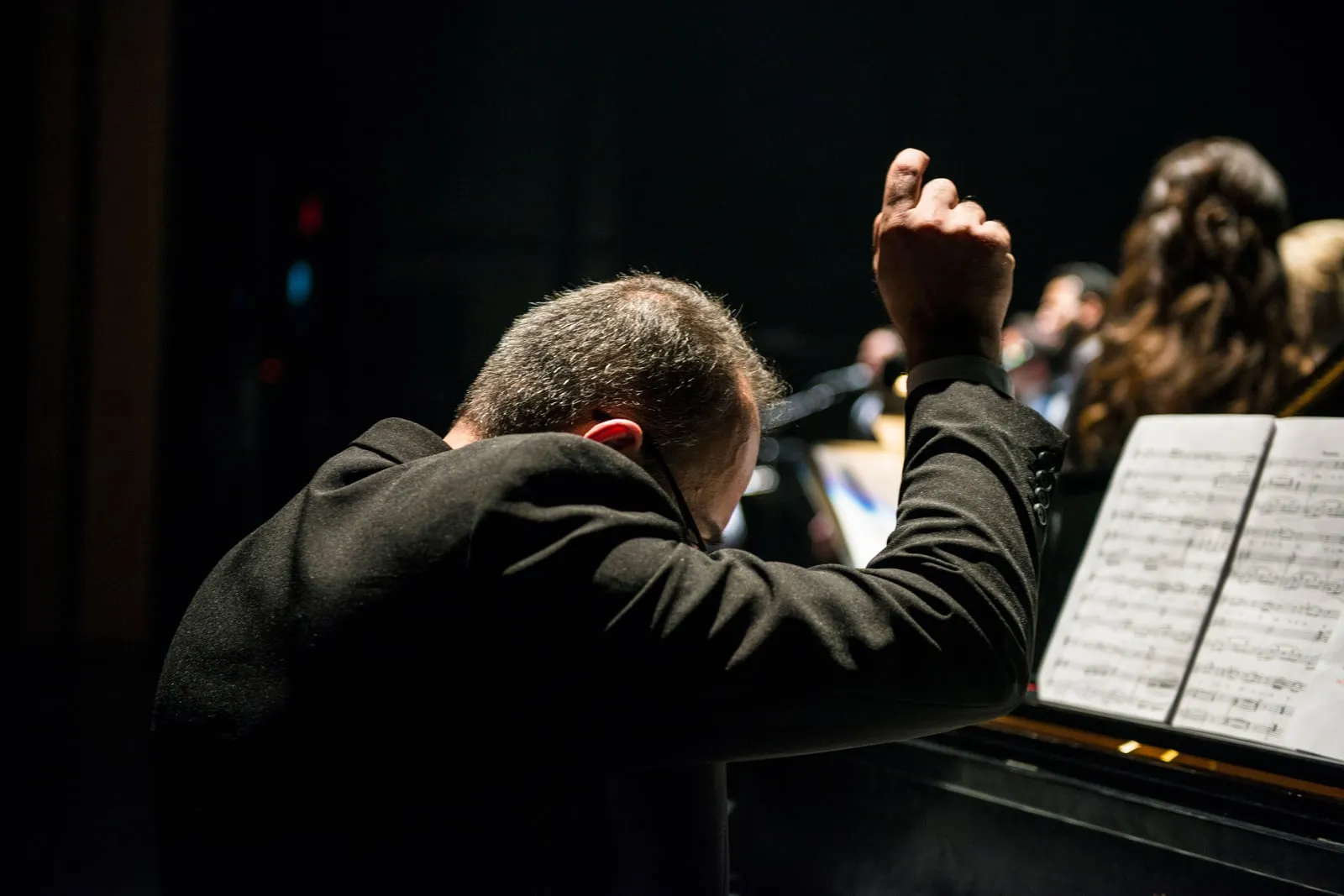 An orchestra conductor leading a group of musicians on stage