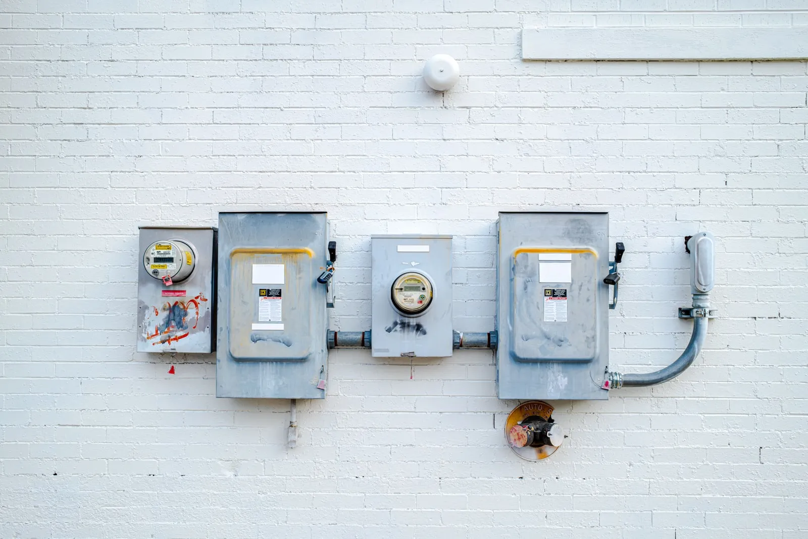 Electricity meters and switch boxes mounted on a white brick wall