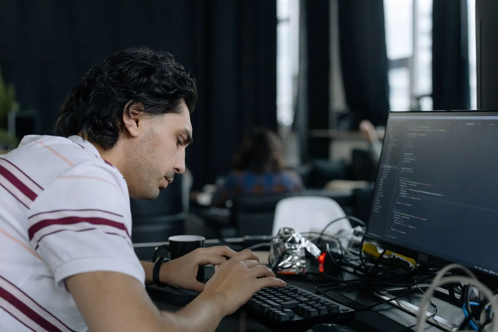 A software developer typing at a keyboard in an office