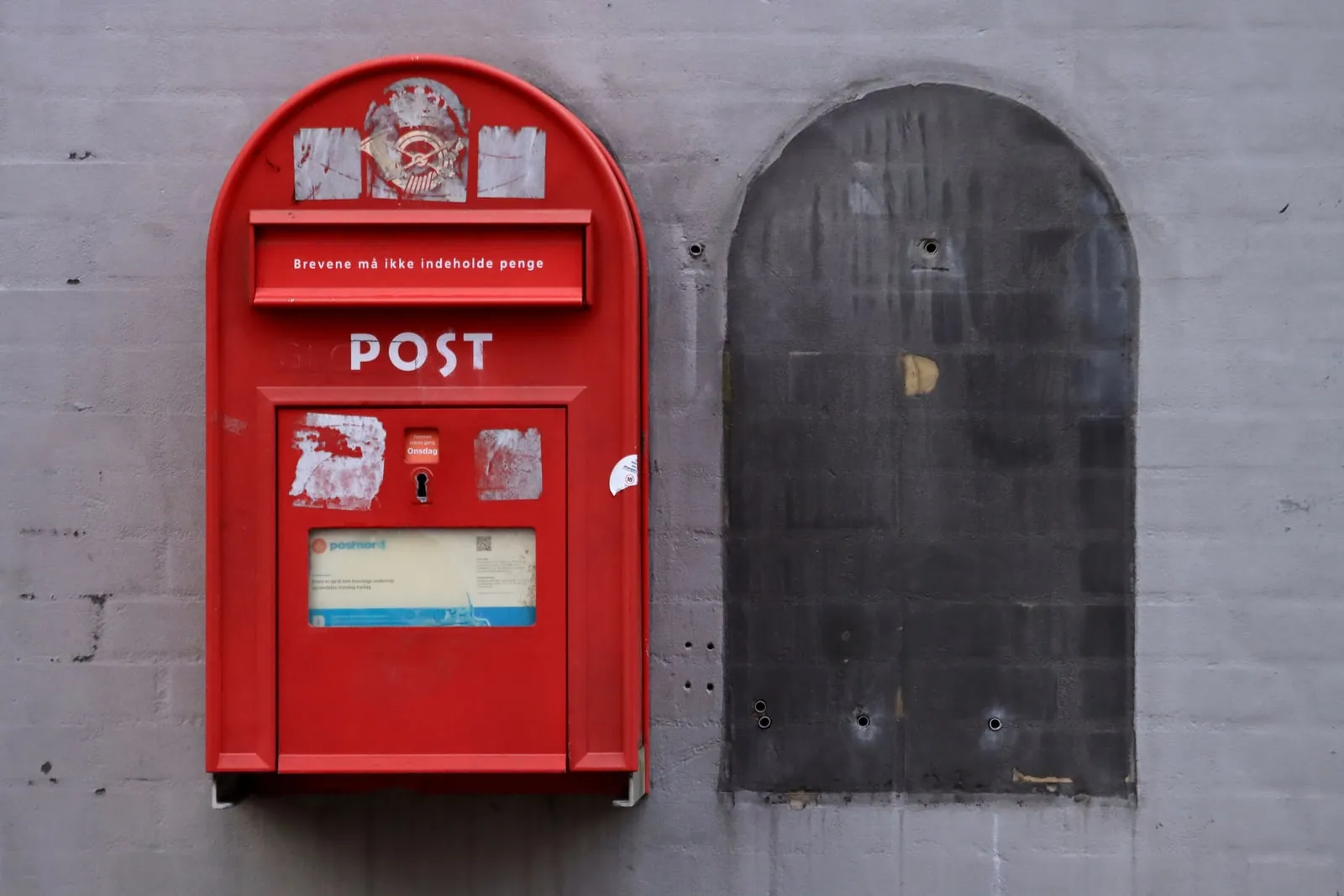A red post box mounted on a concrete wall