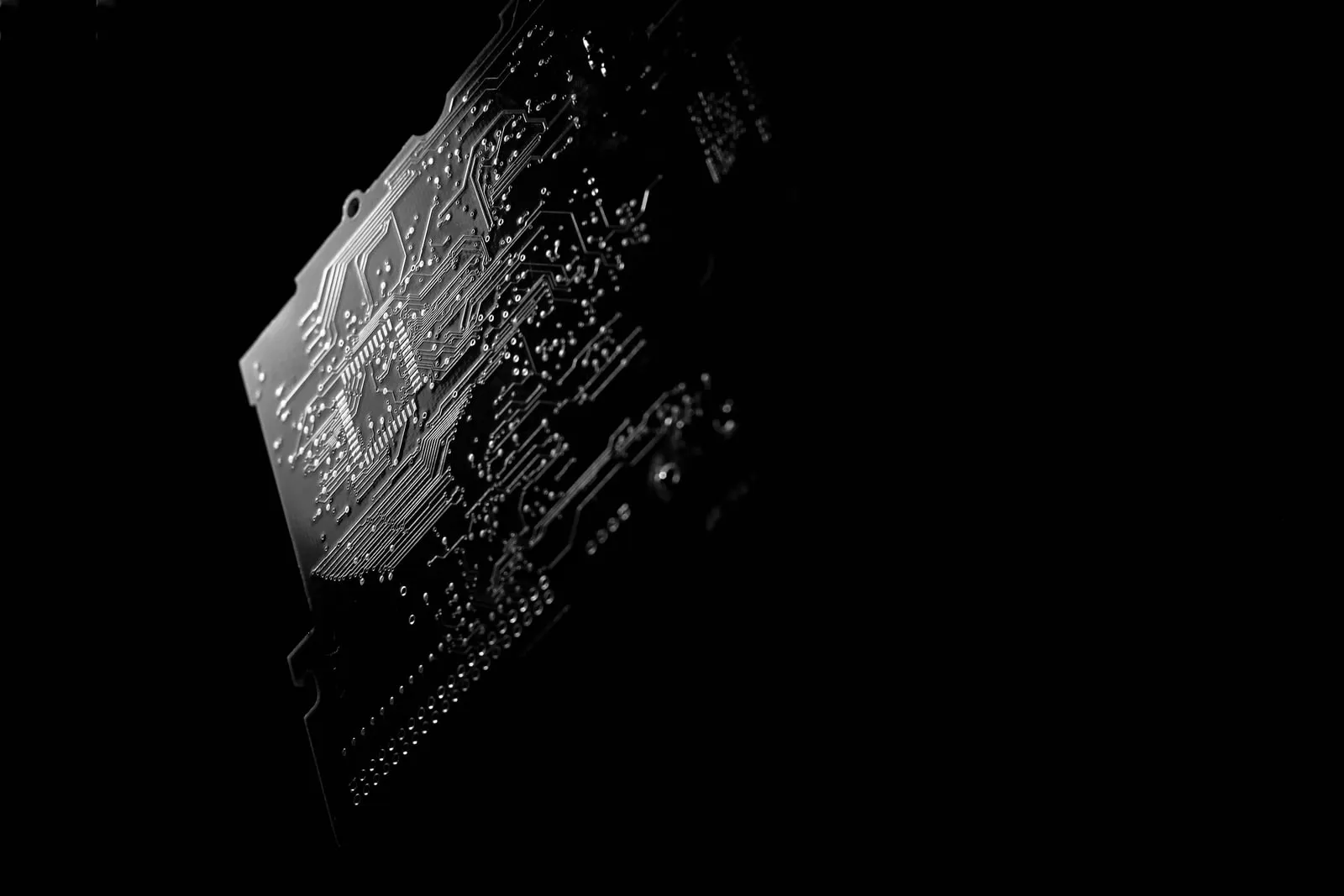 A circuit board lit from one side against a black background