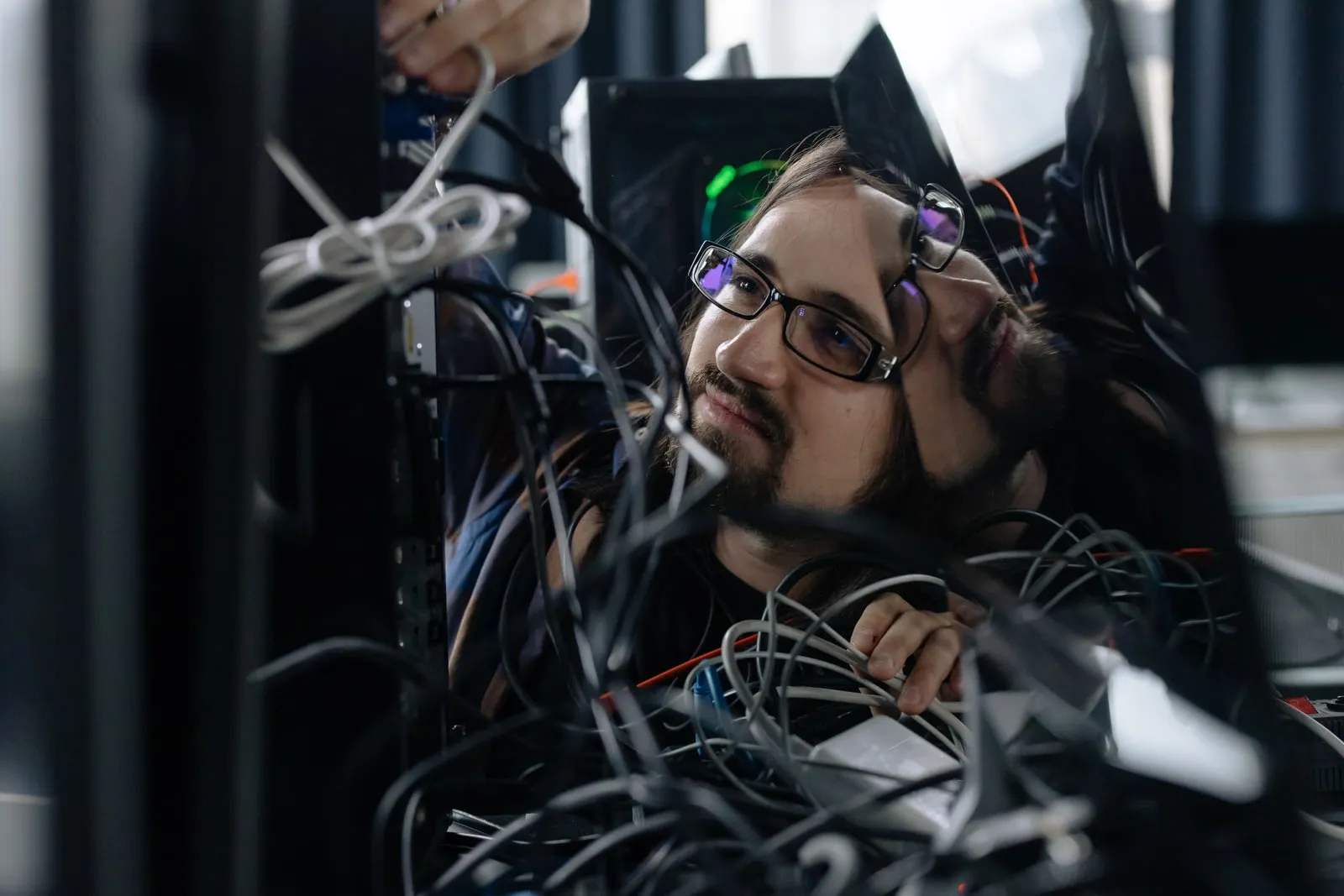 A technician working among cables inside a server rack
