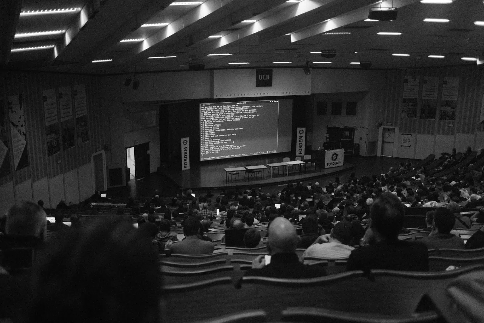 A conference stage with a large screen in front of an audience