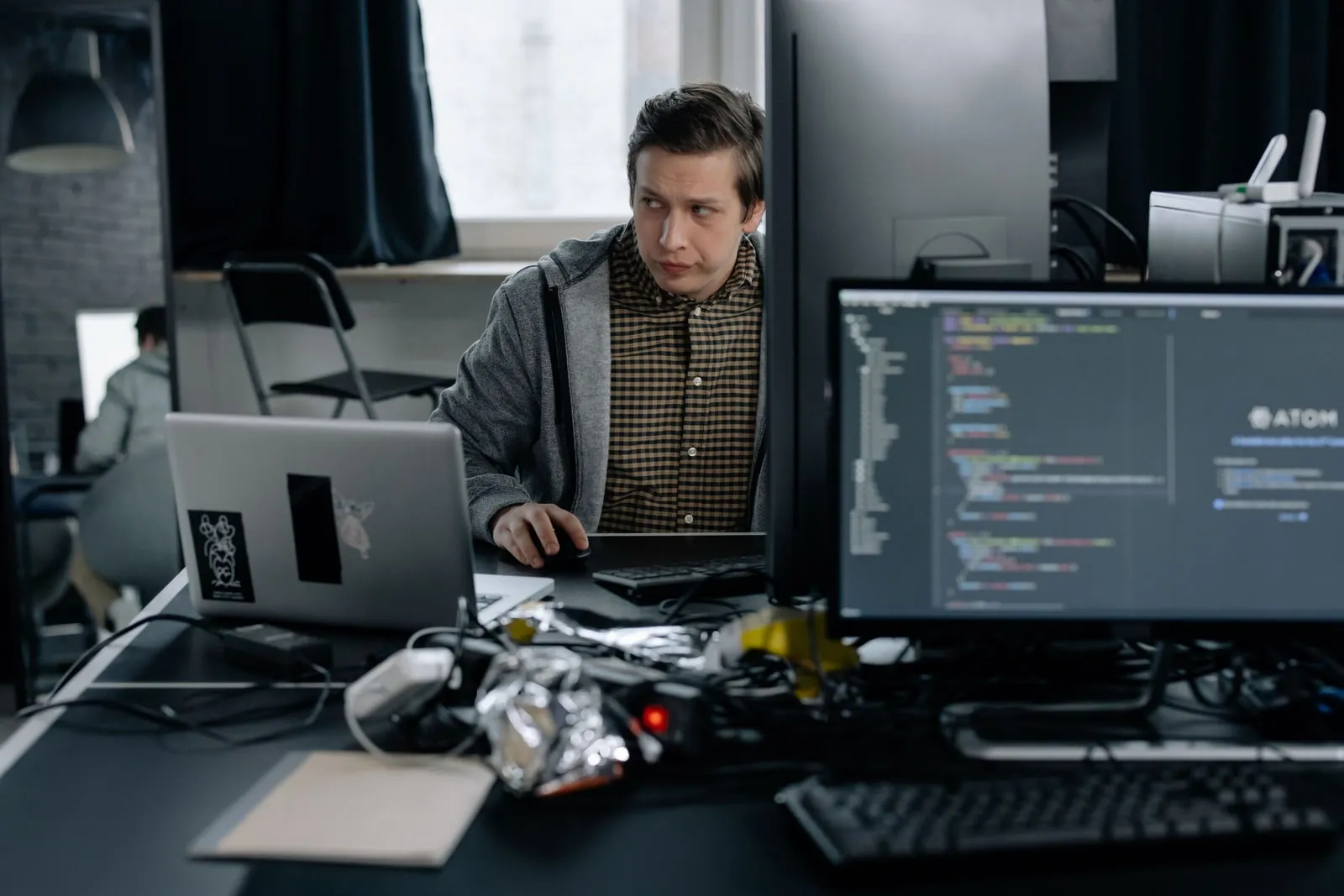 A developer reading code on a laptop screen at a desk
