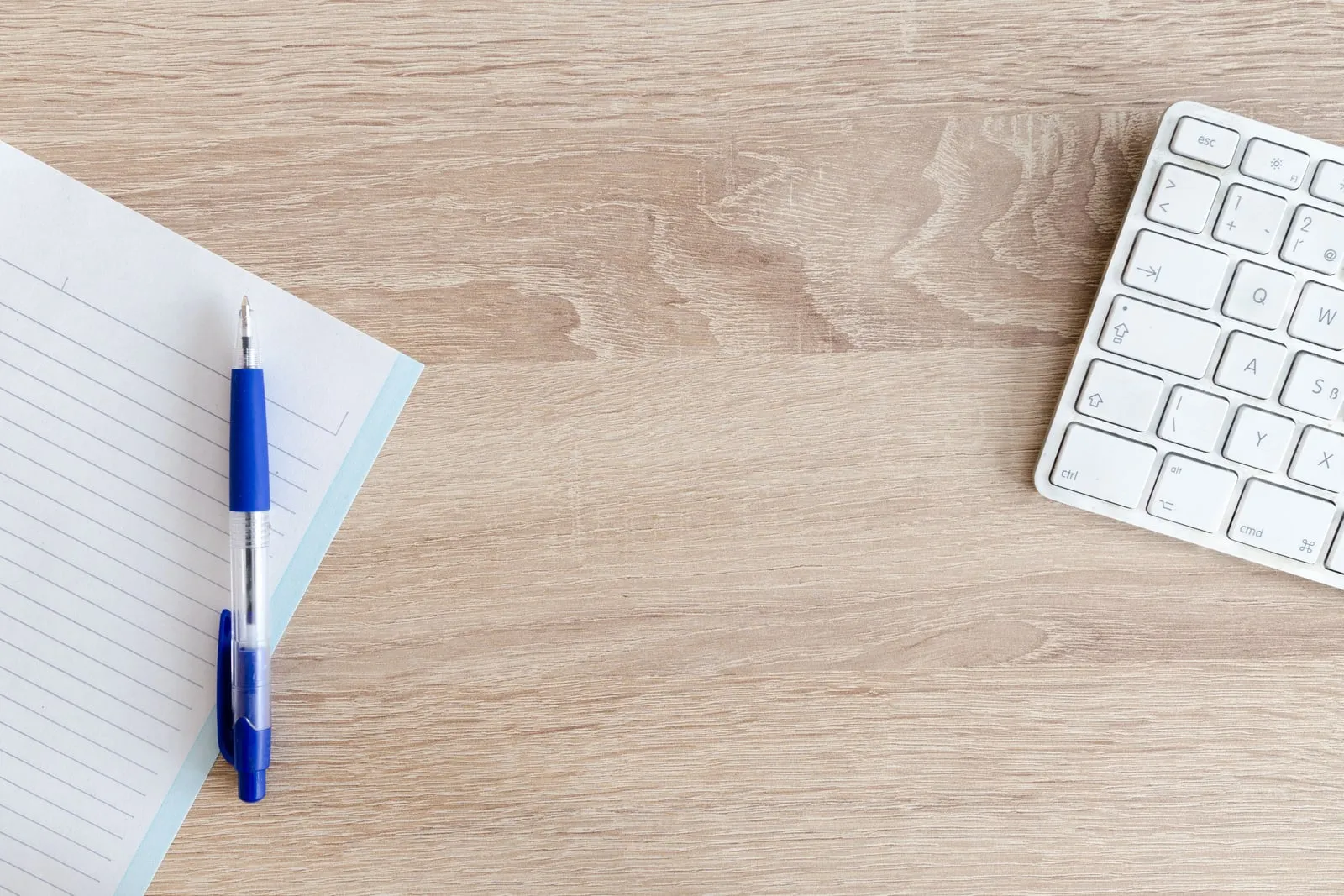 A notebook and pen beside a computer keyboard
