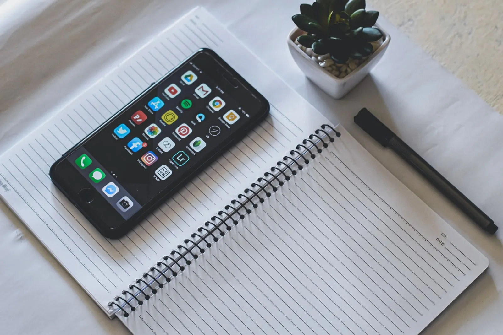 A smartphone lying on a desk beside a notebook