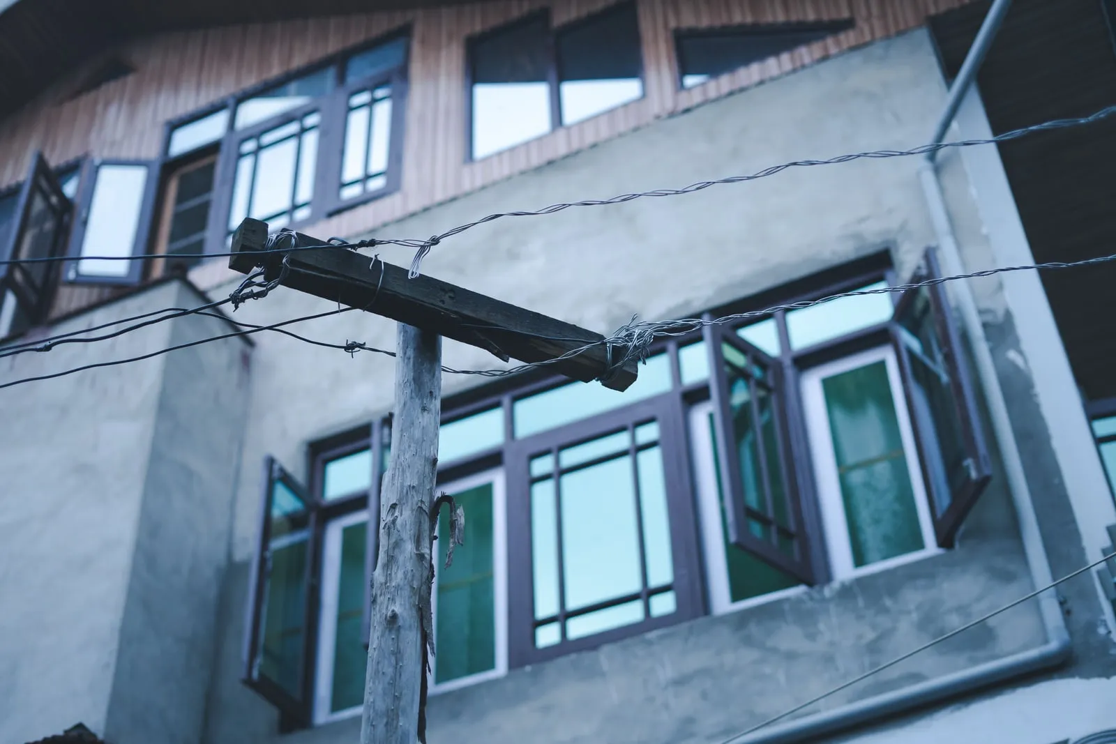 A wooden utility pole and overhead wires in front of a residential building