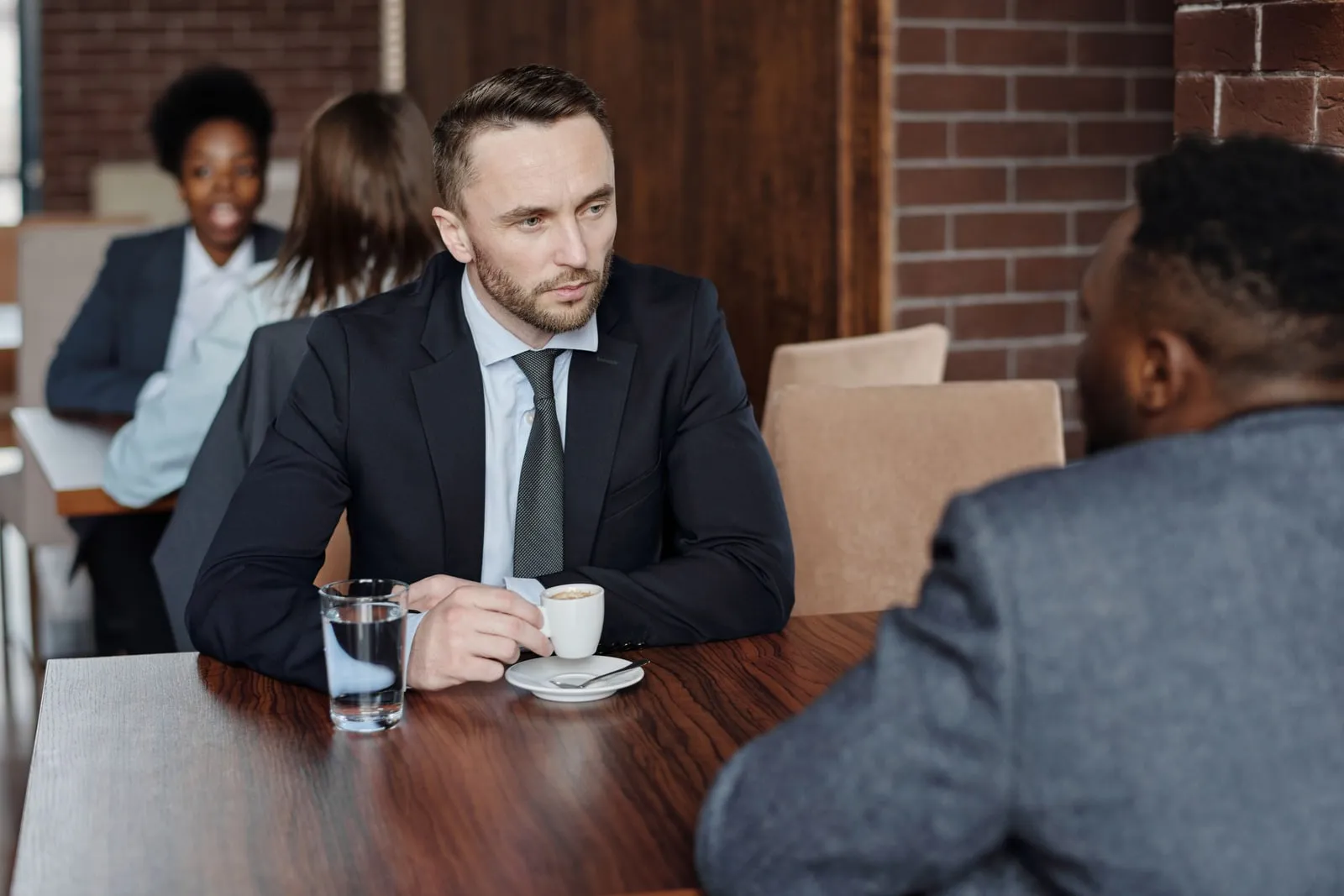 Two people talking across a cafe table with coffee cups