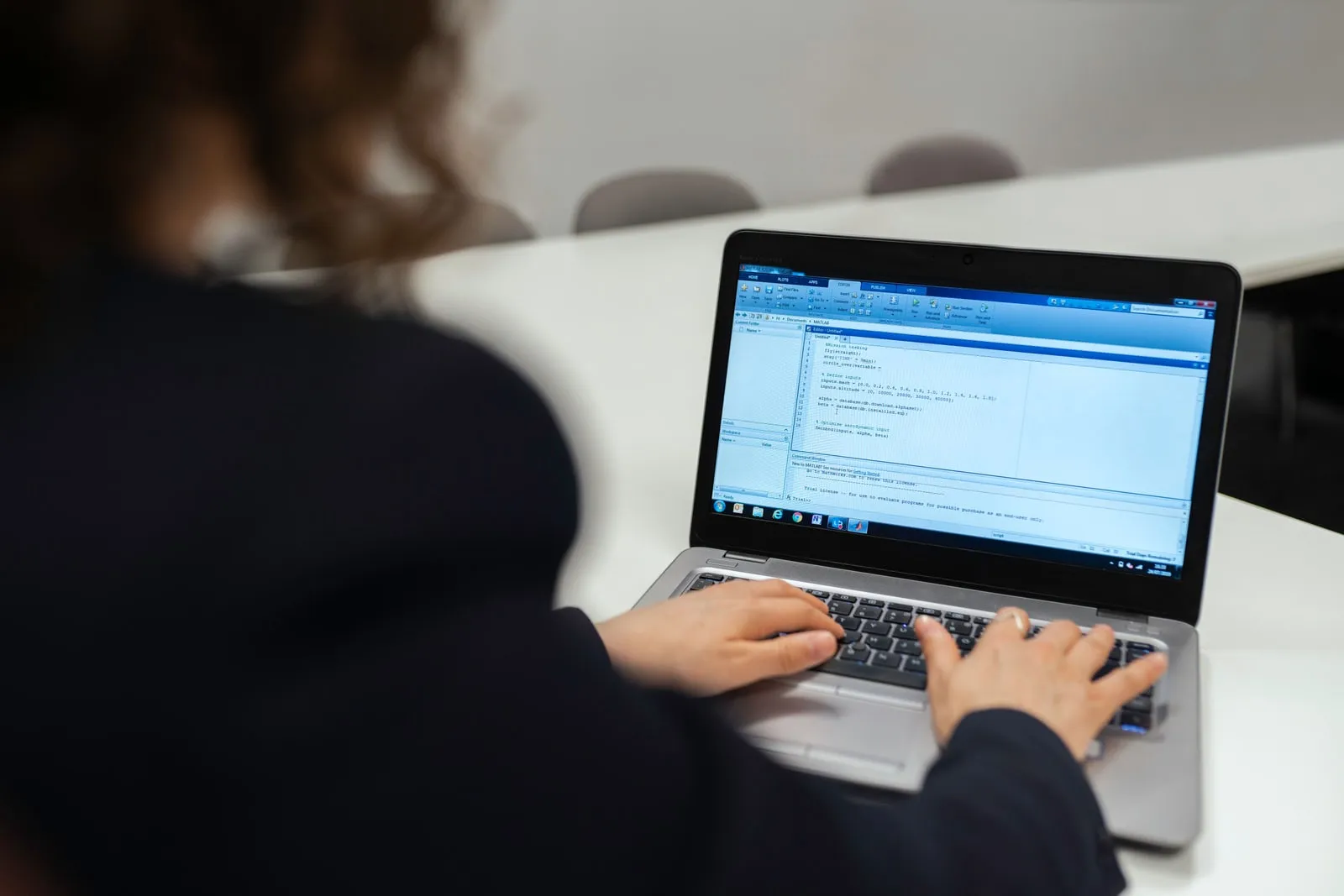 A software engineer typing on a laptop in a bright office