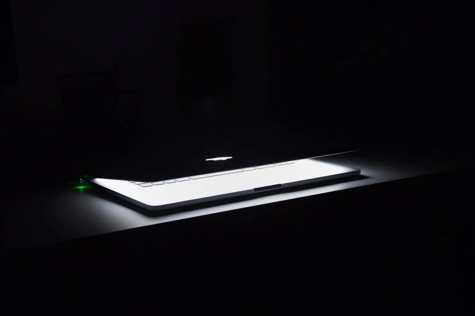 A laptop open on a desk in a dark room