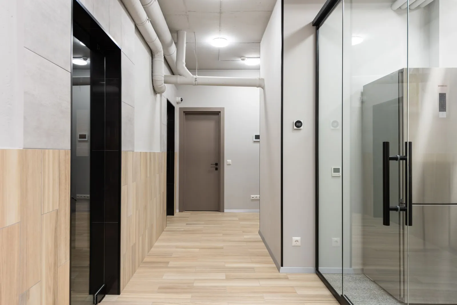 An empty office corridor lined with glass doors
