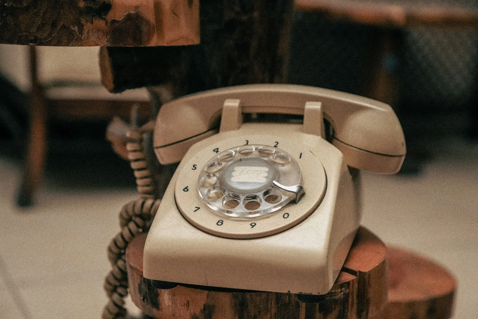 An old rotary dial telephone resting on a wooden stool