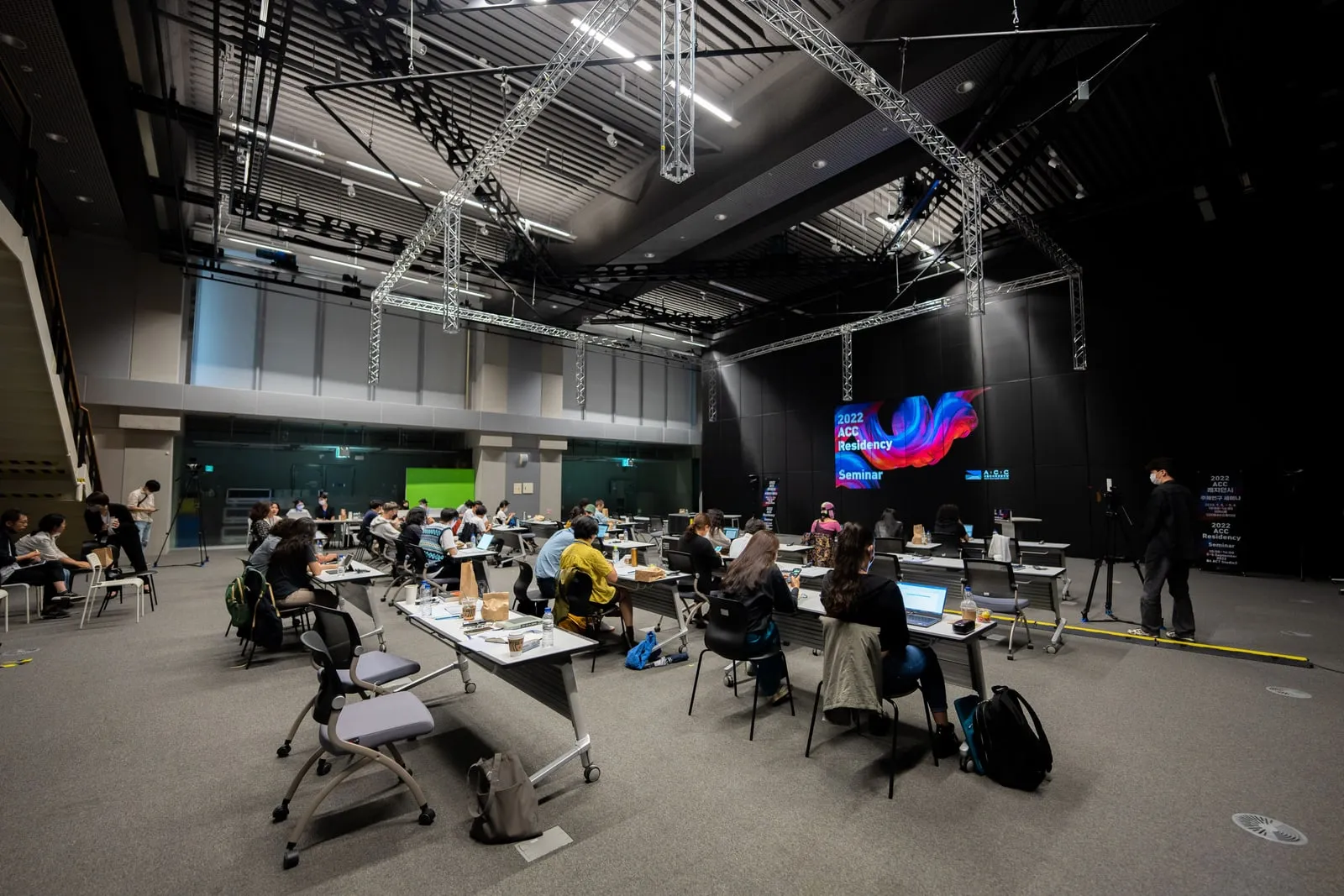 People seated at desks in a large hall
