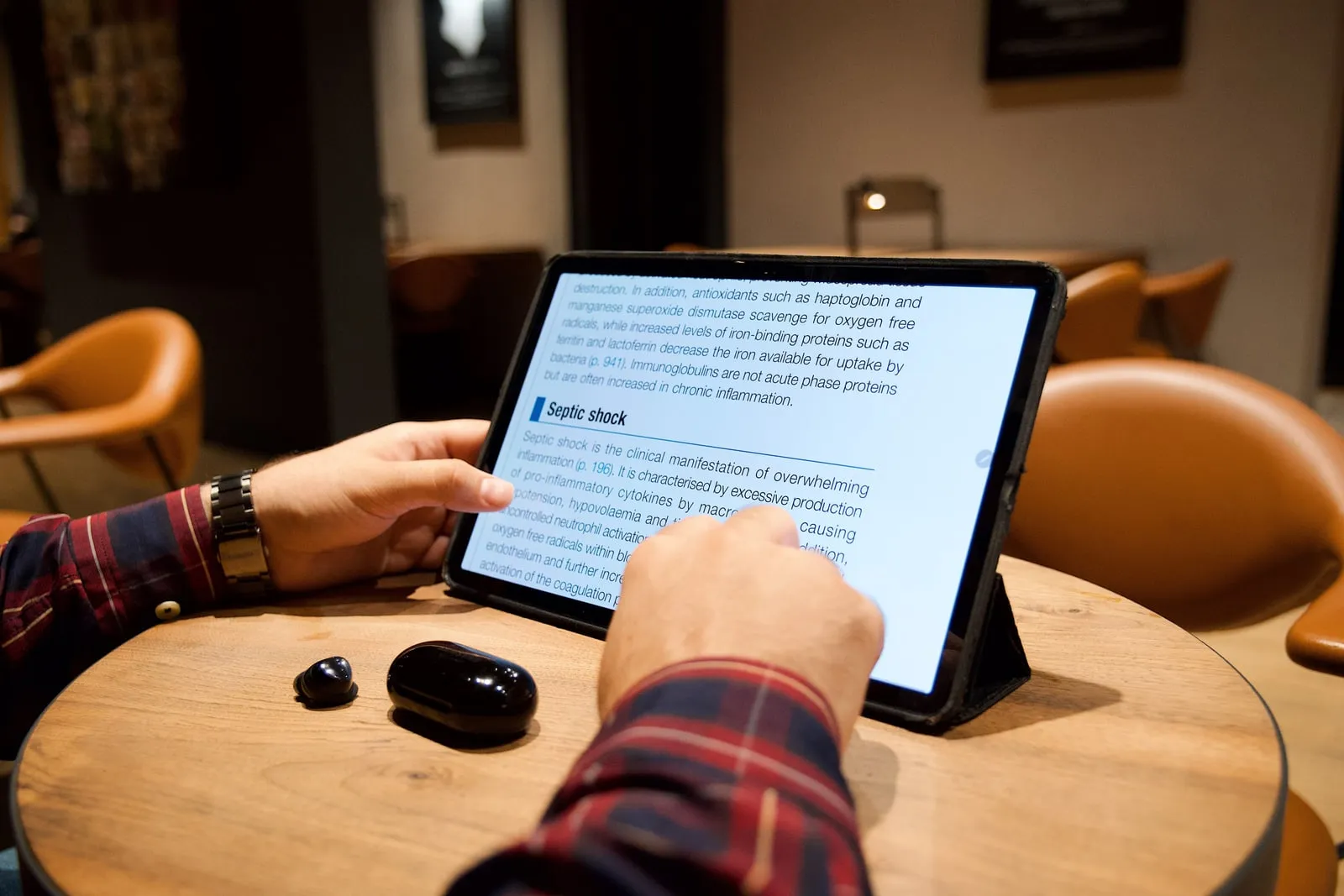 A person scrolling through text on a tablet at a table