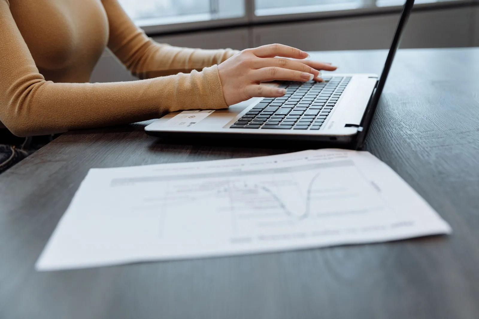 Hands typing a document on a laptop keyboard