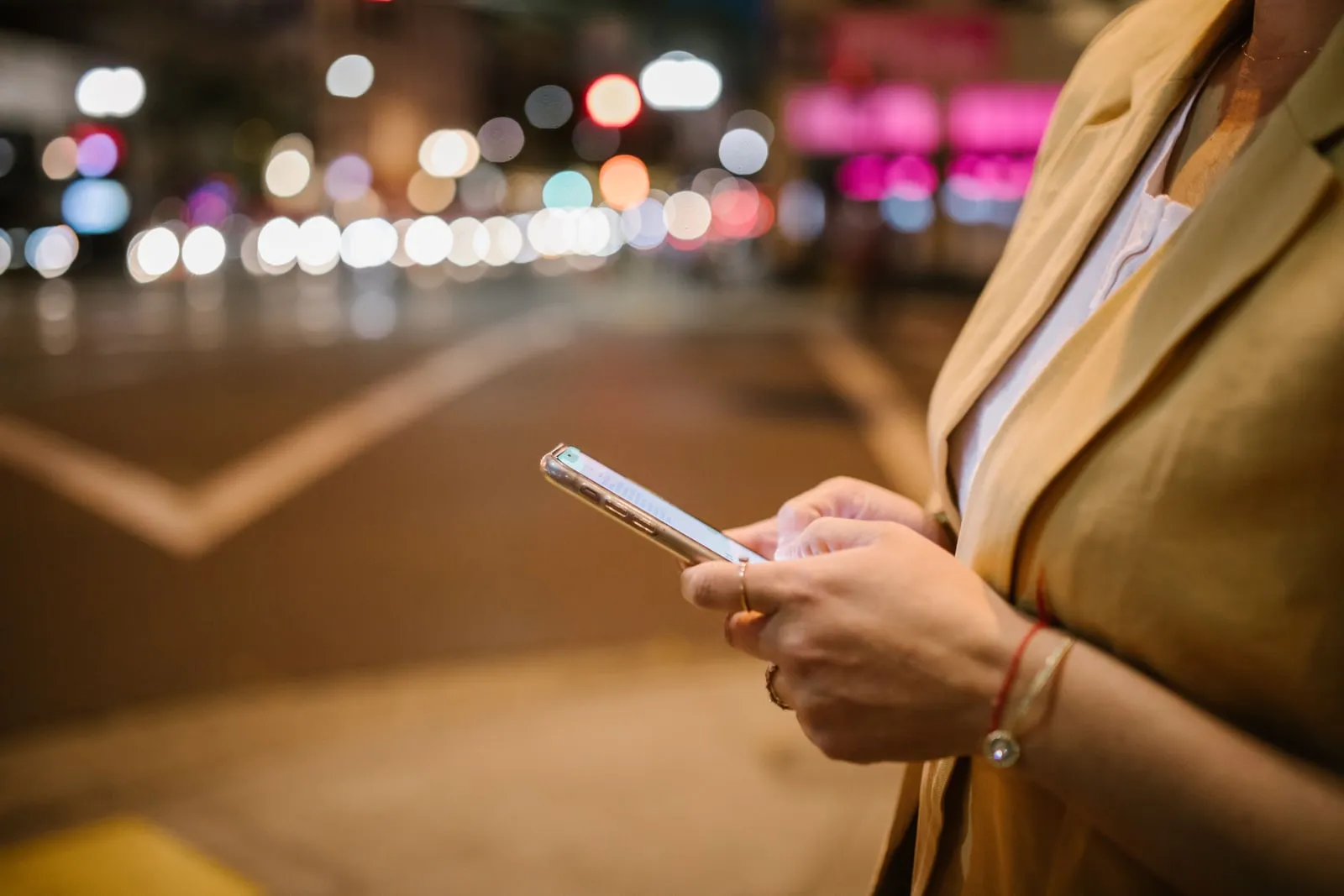 Des mains tenant un téléphone dans une rue au crépuscule