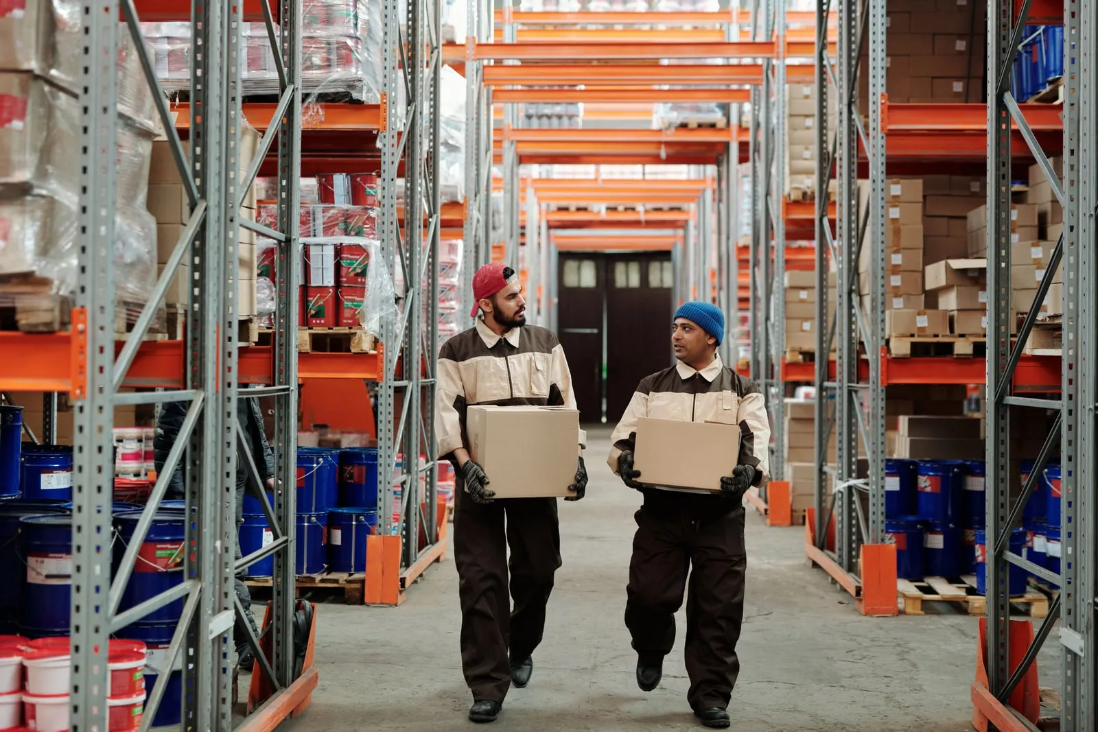 Warehouse workers carrying boxes between shelves
