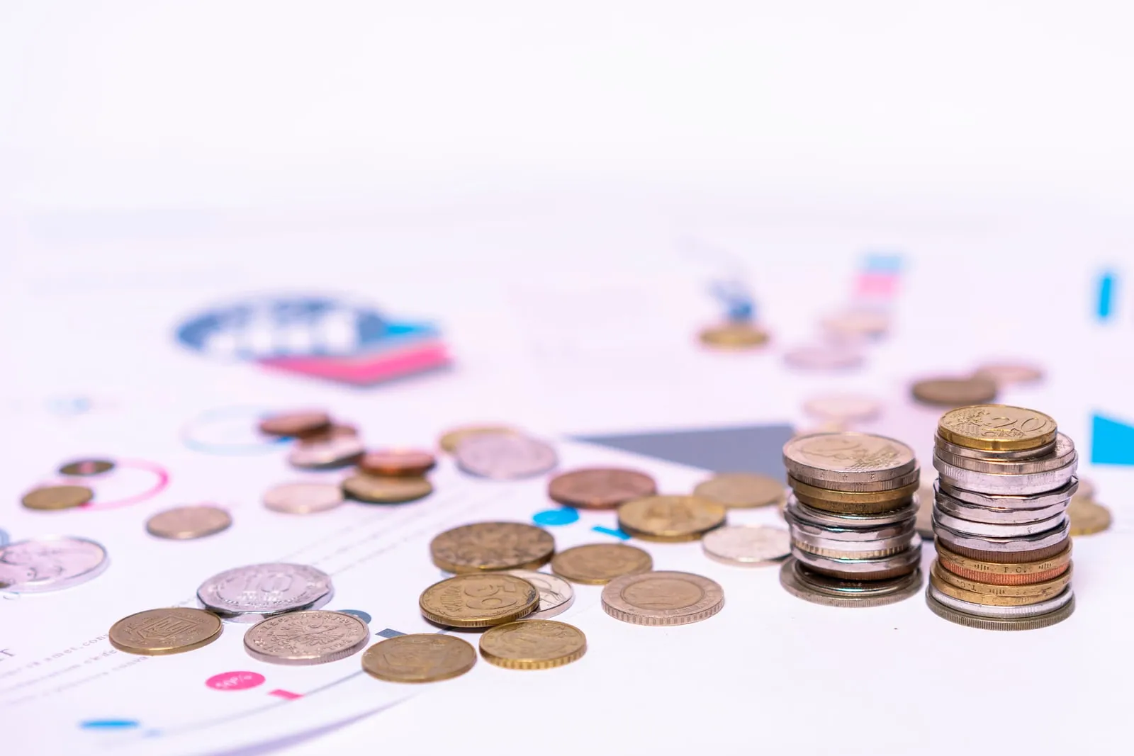 Stacked coins beside a printed financial report