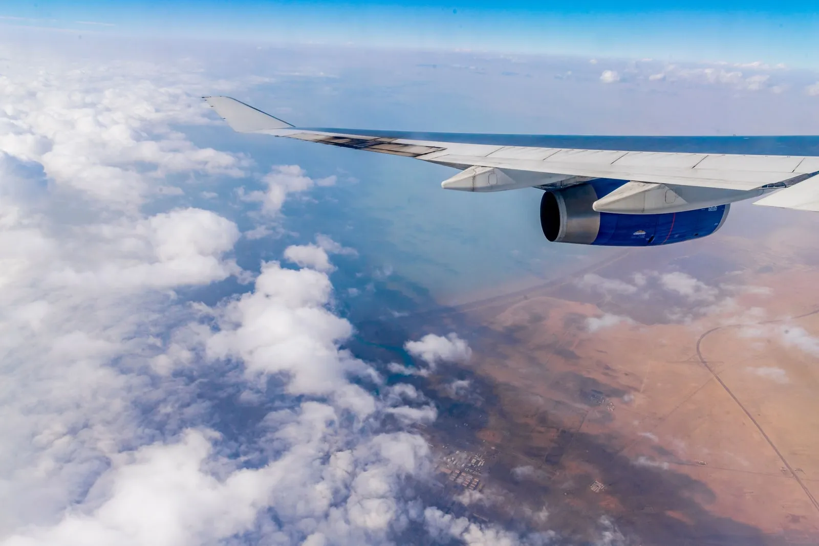 An aeroplane wing and clouds seen from a cabin window