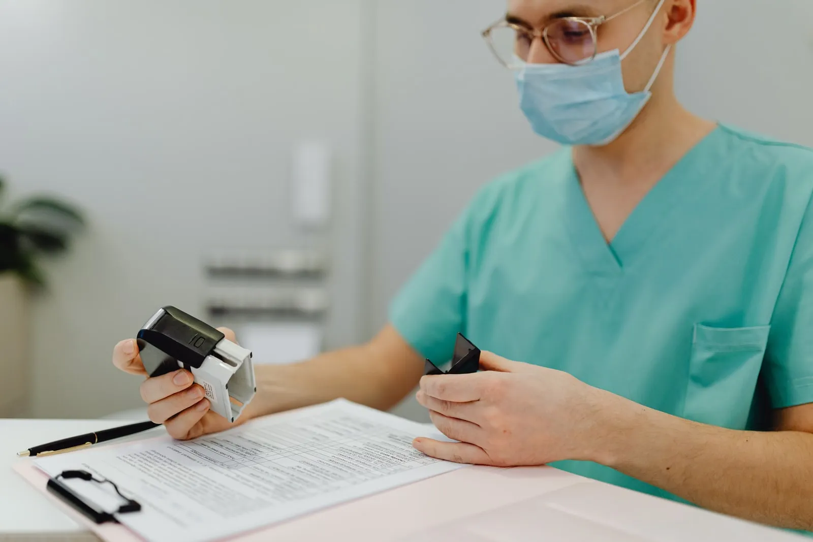 A health worker in scrubs reviewing paperwork at a desk