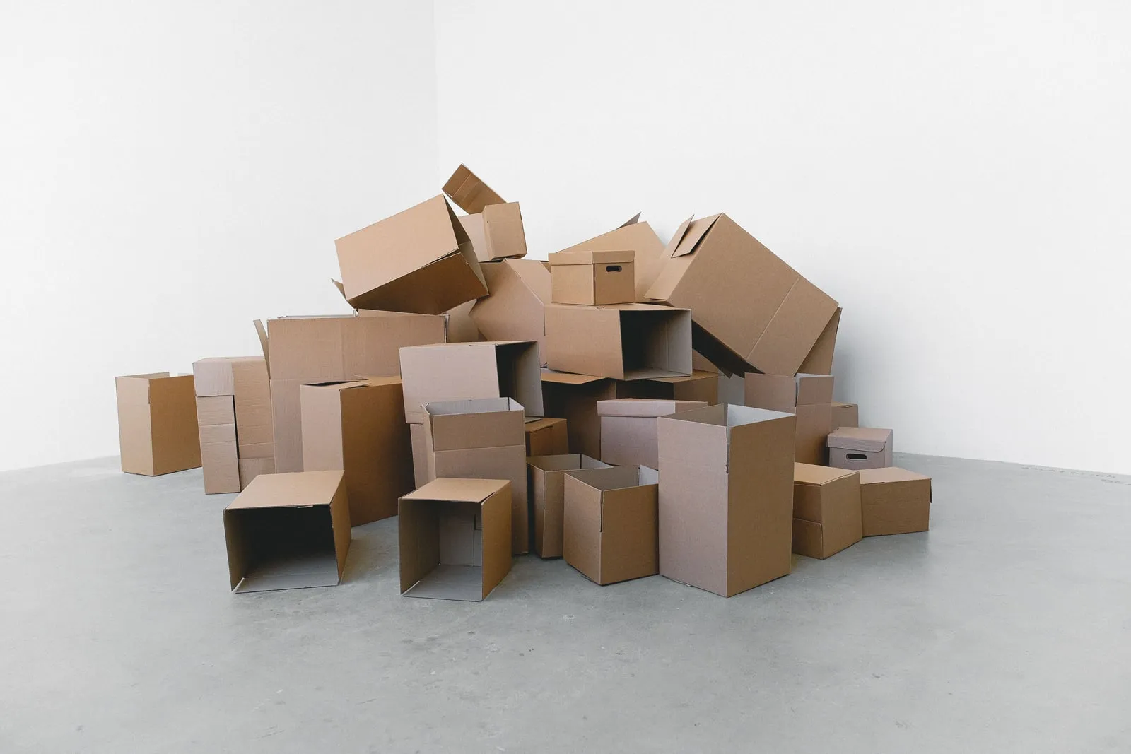 A heap of empty cardboard boxes in a bare white room