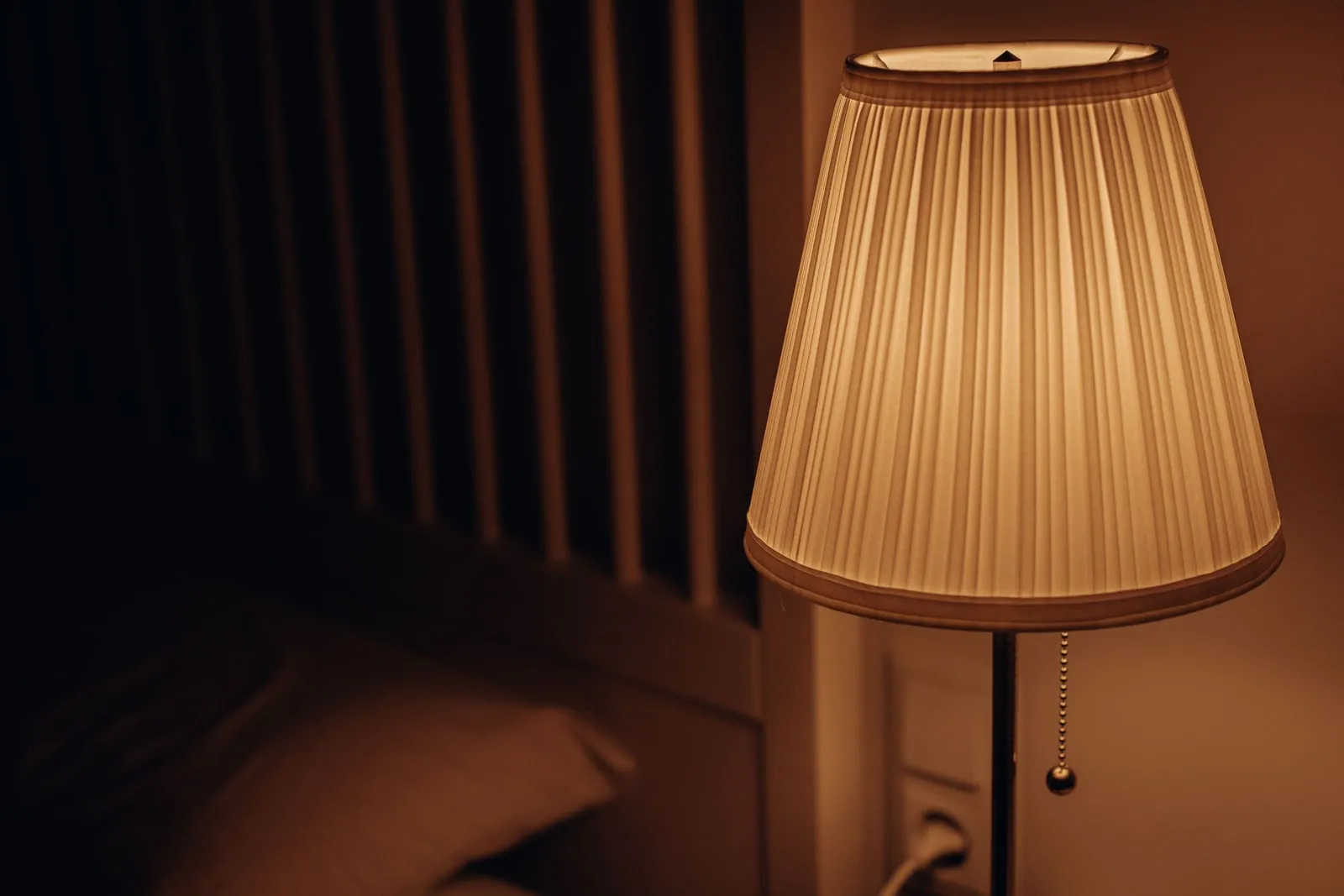 A lit lamp beside a bed