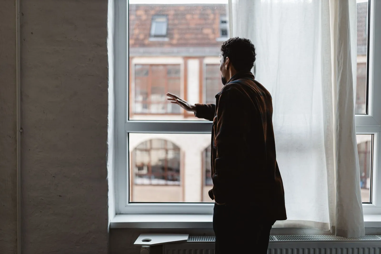 A person standing alone looking out of an office window