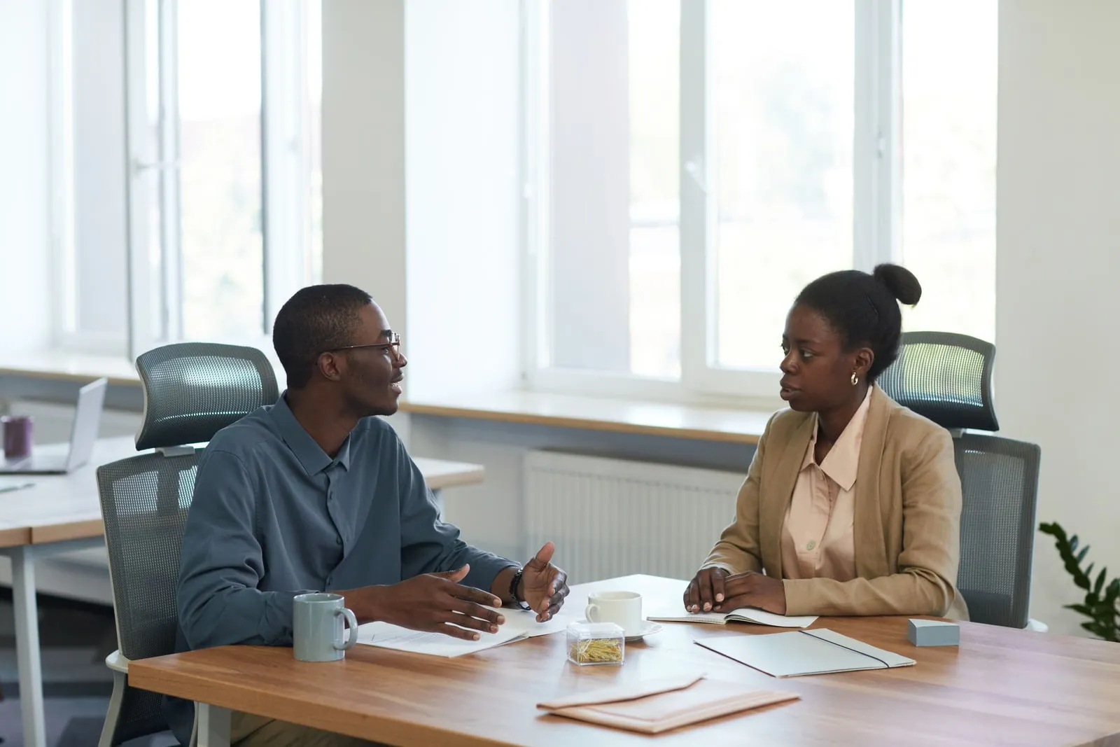 Two colleagues talking at a desk in an office