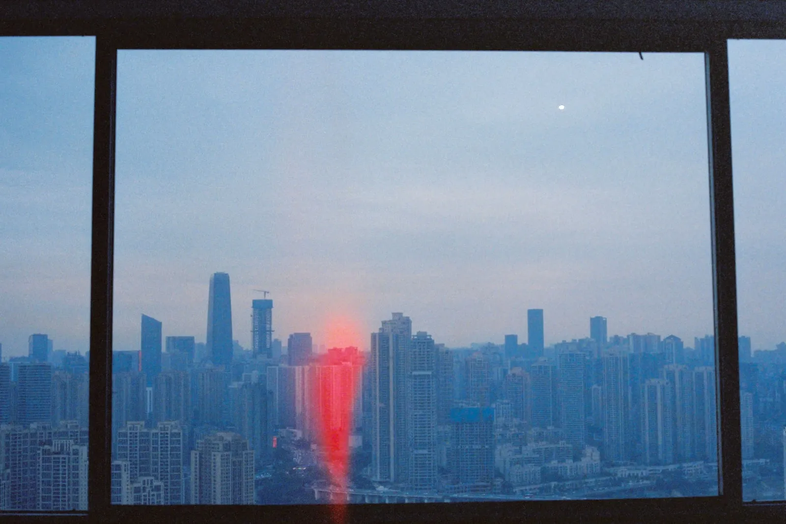A city skyline seen through a tall window at dusk