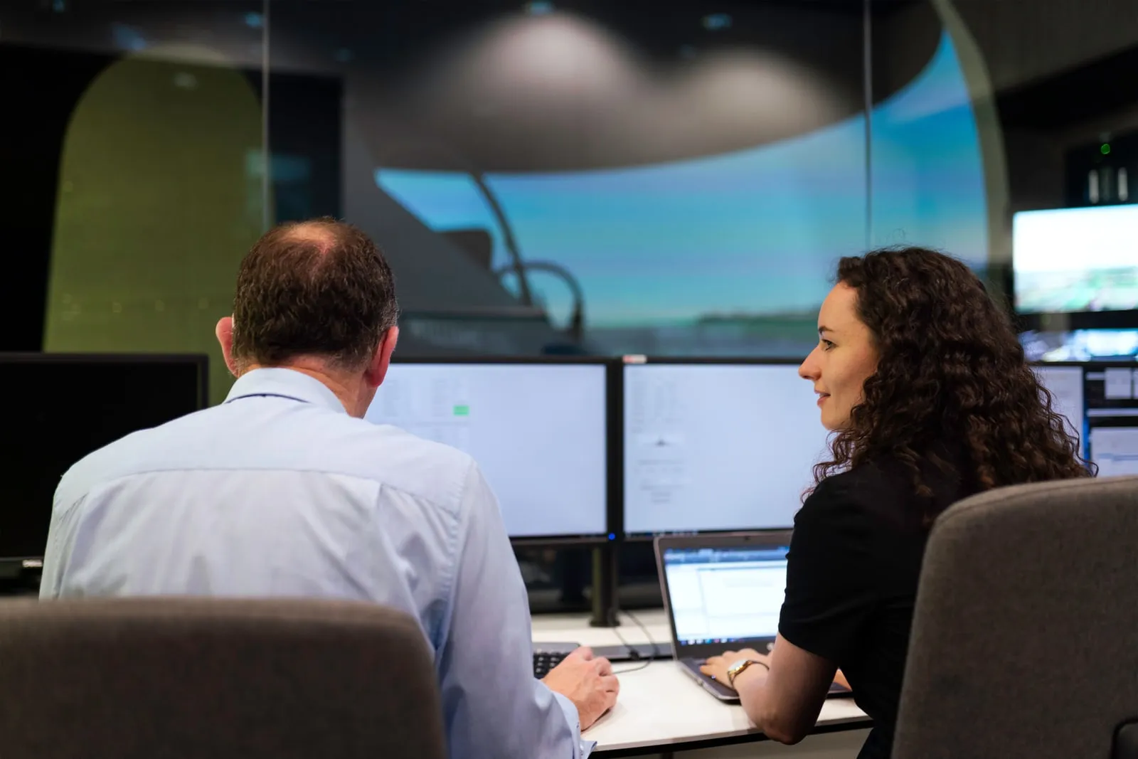 Engineers discussing data shown on computer monitors