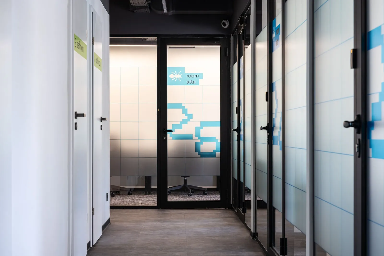 An office corridor with glass-walled meeting rooms