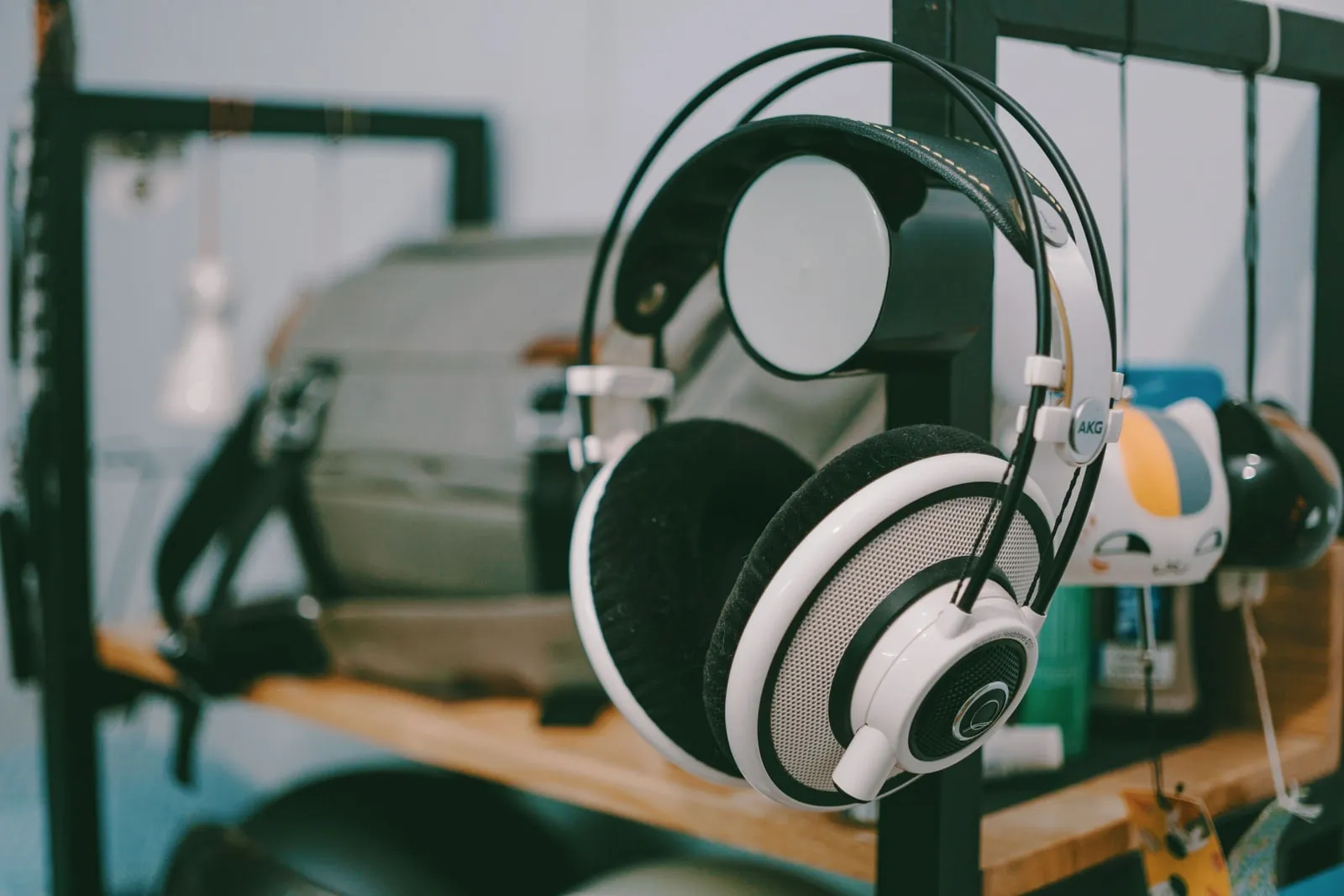 A pair of over-ear headphones hanging from a stand on a shelf