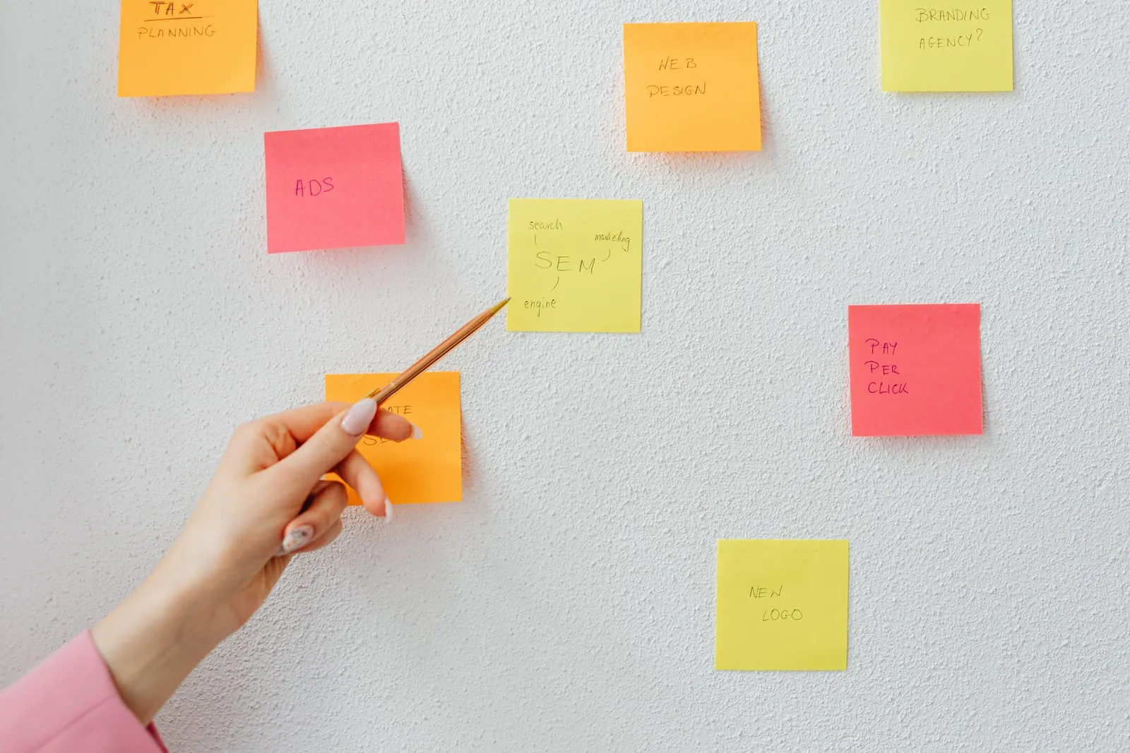 A hand pointing at marketing sticky notes on a wall
